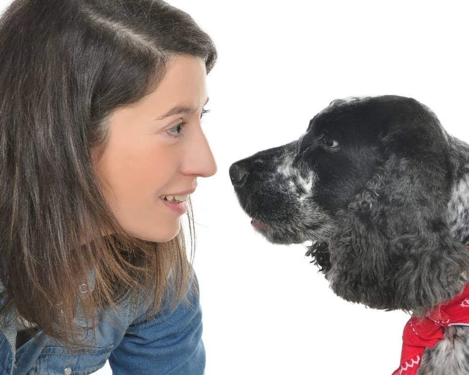 Una mujer y un perro de orejas largas mirando uno al otro con cercanía.