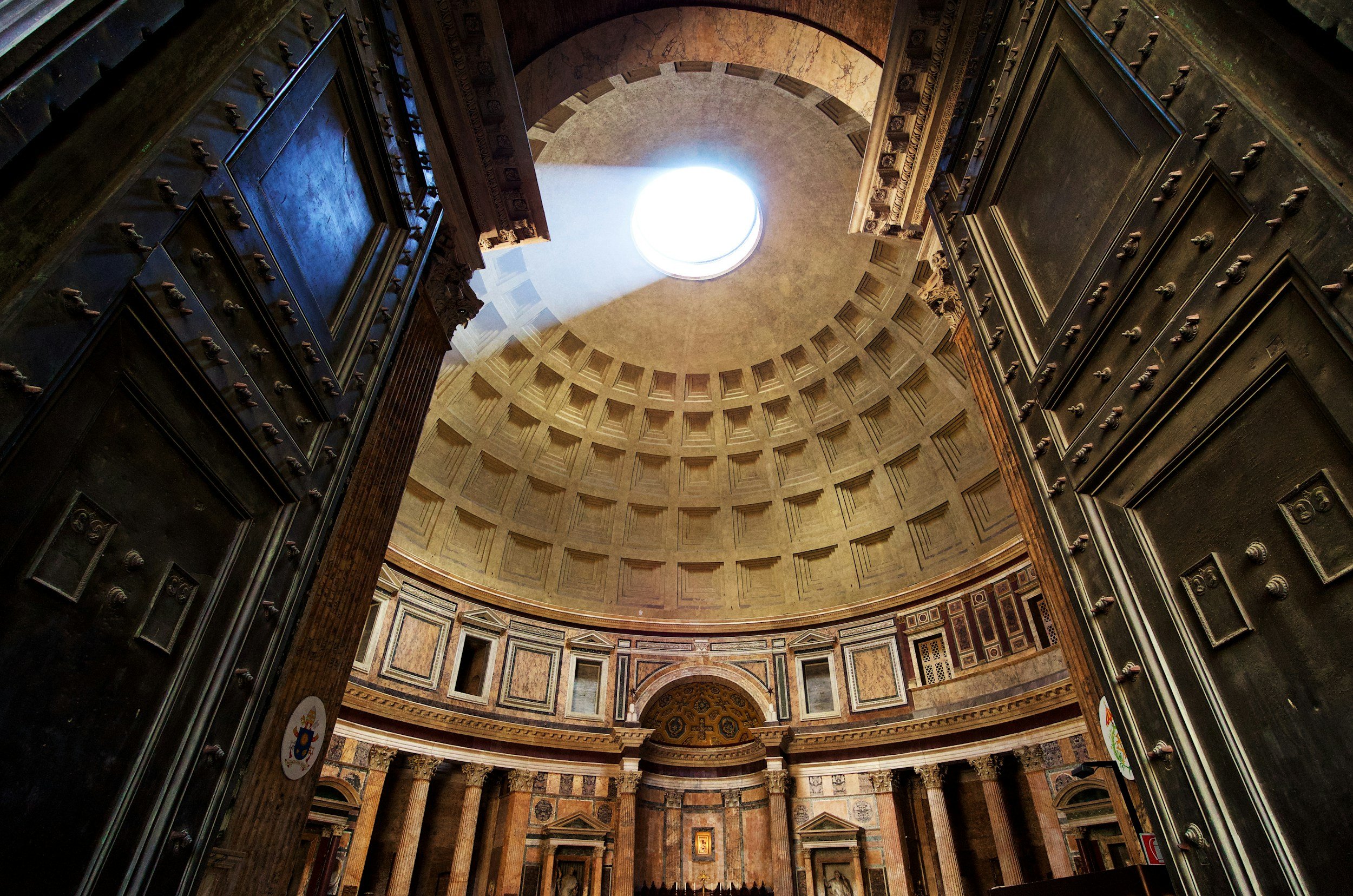 Inside view of a grand, historic domed building, likely a church or cathedral, with a circular skylight at the top allowing natural light to shine in.