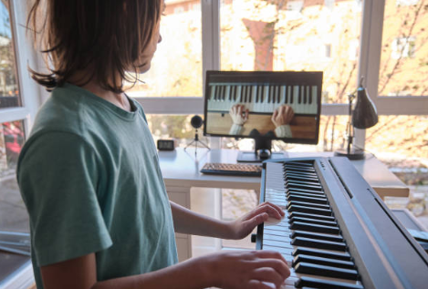 Enfant jouant du piano électronique dans une pièce lumineuse avec un ordinateur affichant un clavier de piano