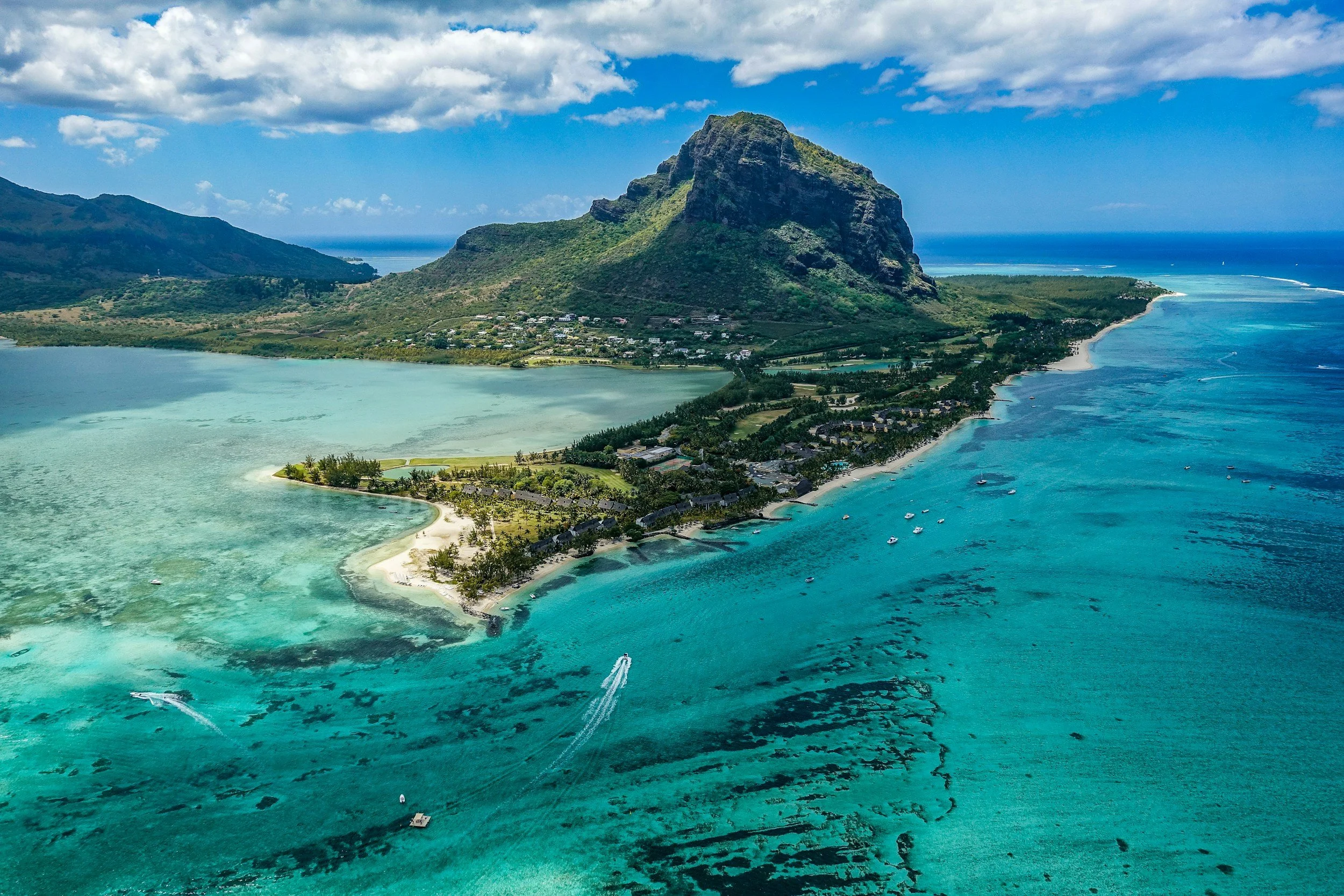 Luftaufnahmen der Insel Mauritius mit türkisfarbenem Wasser, weißen Sandstränden und einer grünen Wald- und Felsenlandschaft.