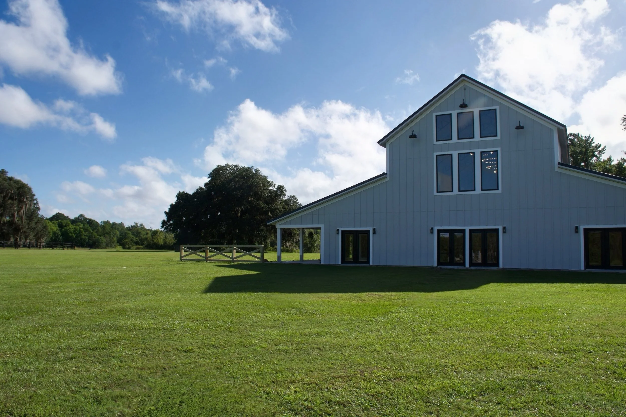 Southern-inspired, modern wedding venue exterior with white walls, porch, and scenic landscaping.