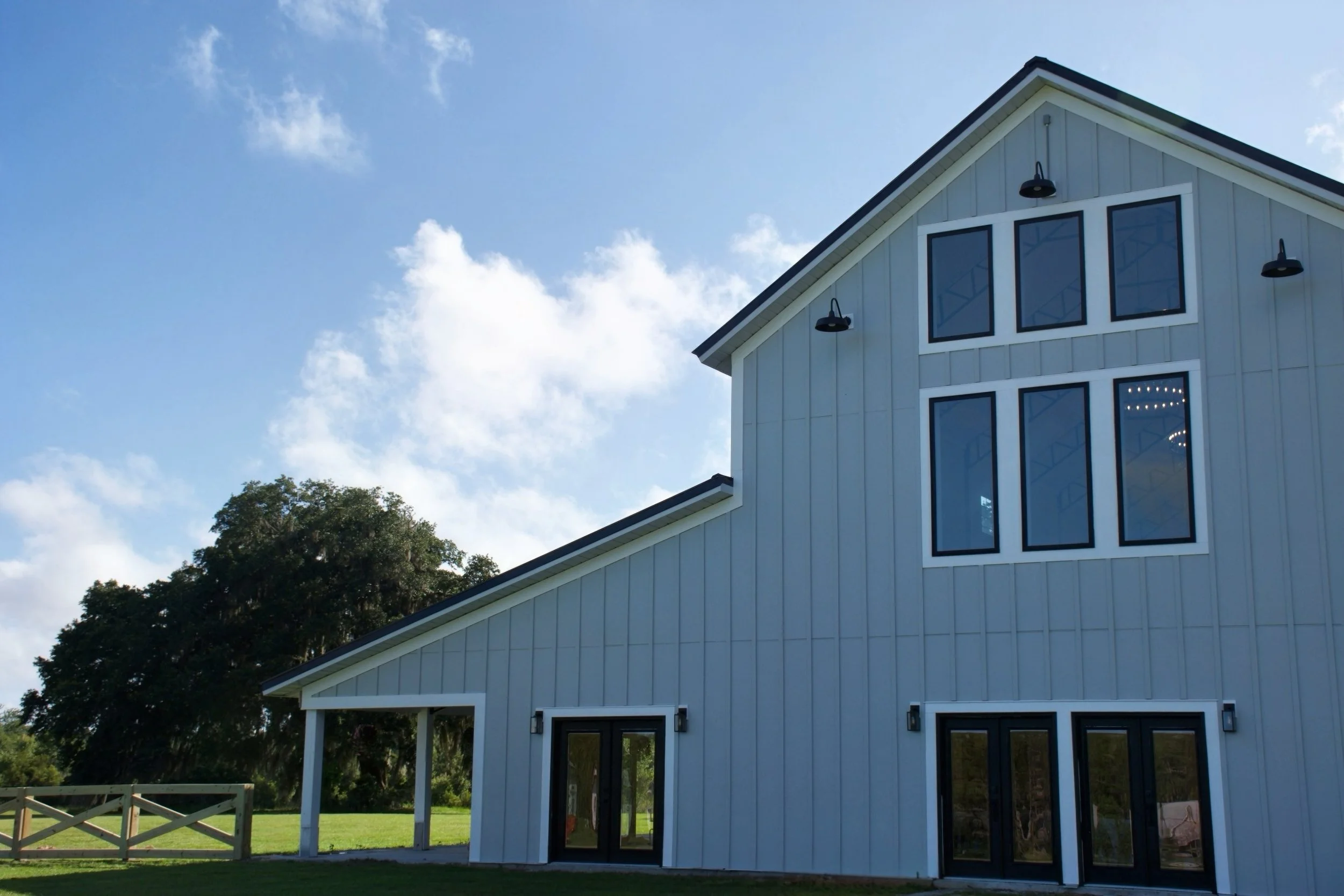 Southern-inspired, modern wedding venue exterior with white walls, porch, and scenic landscaping.
