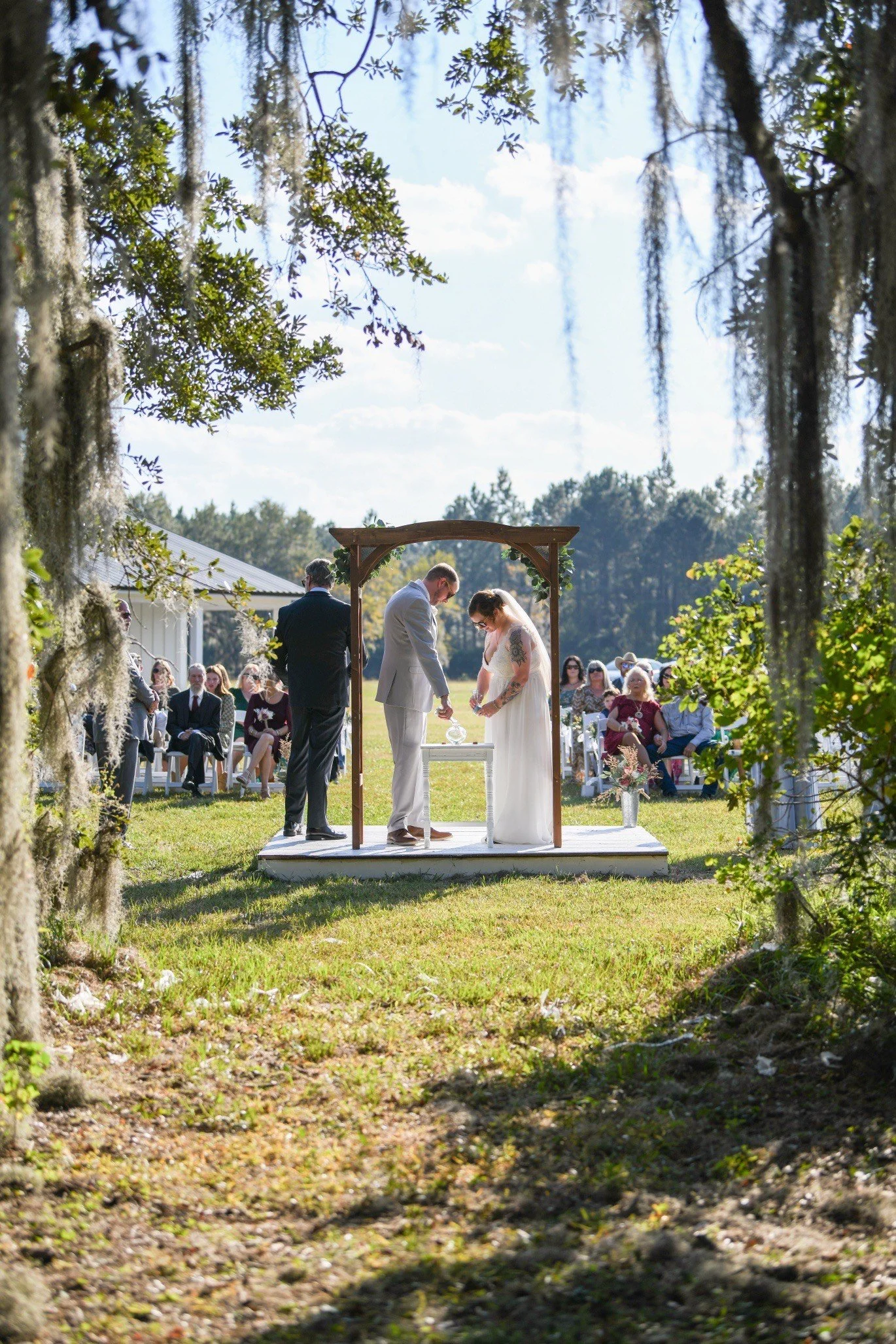 Bride and groom exchanging vows under large oak tree at Southern Georgia wedding venue.
