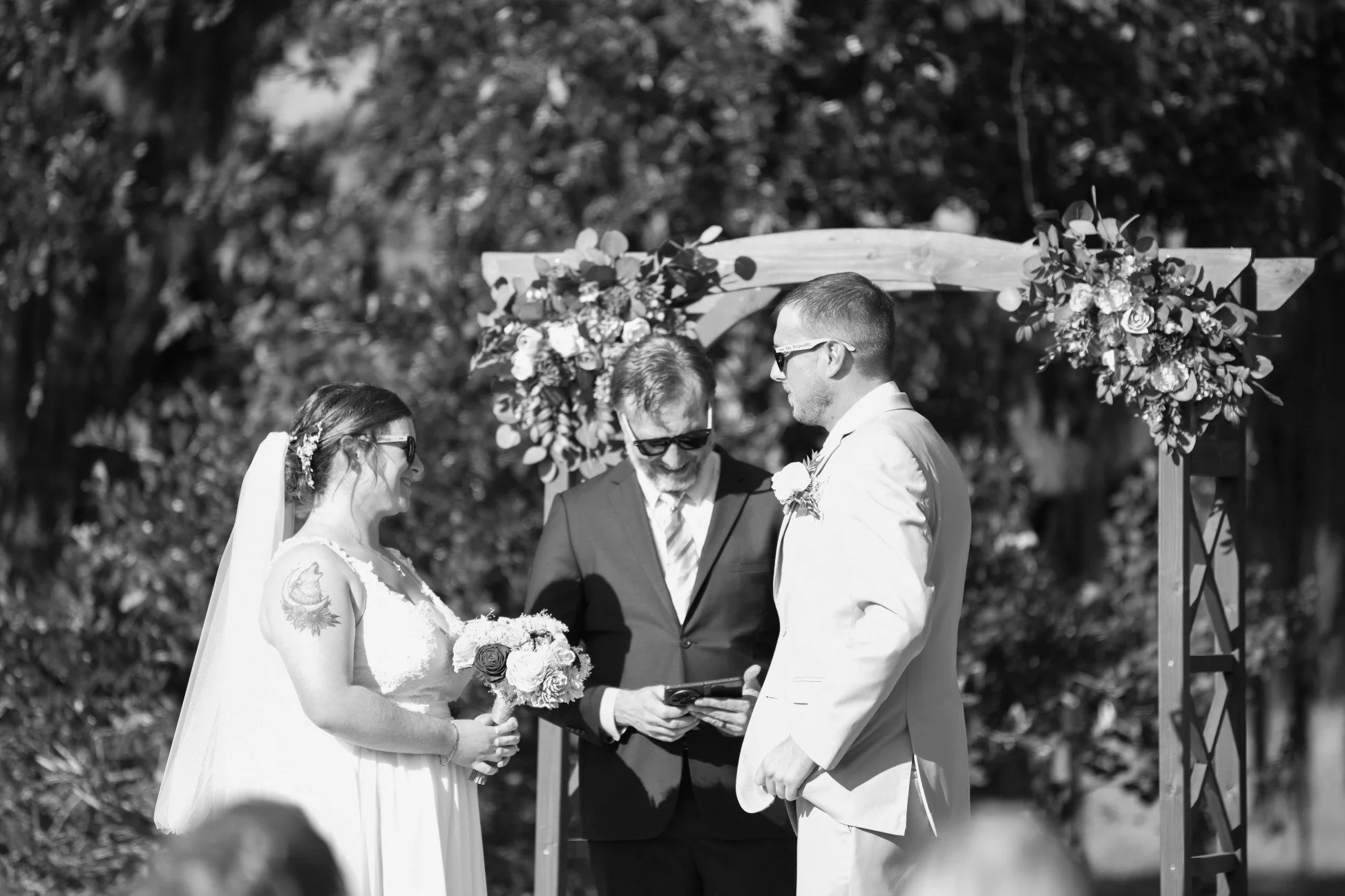 Bride and groom exchanging vows under large oak tree at Southern Georgia wedding venue.