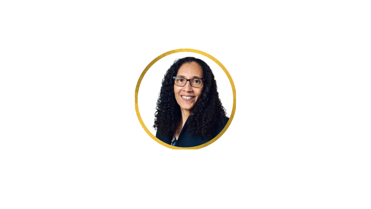 A woman with curly hair, glasses, and a dark blazer, smiling in a professional headshot, surrounded by colorful geometric shapes.
