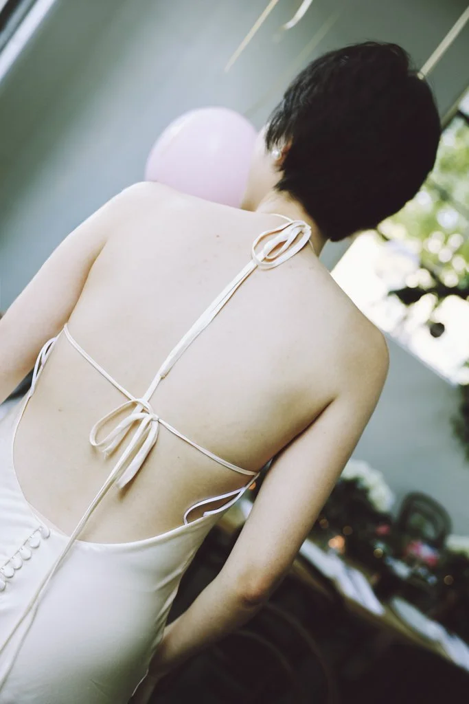 Editorial bridal portrait showing the back detail of a white wedding dress.