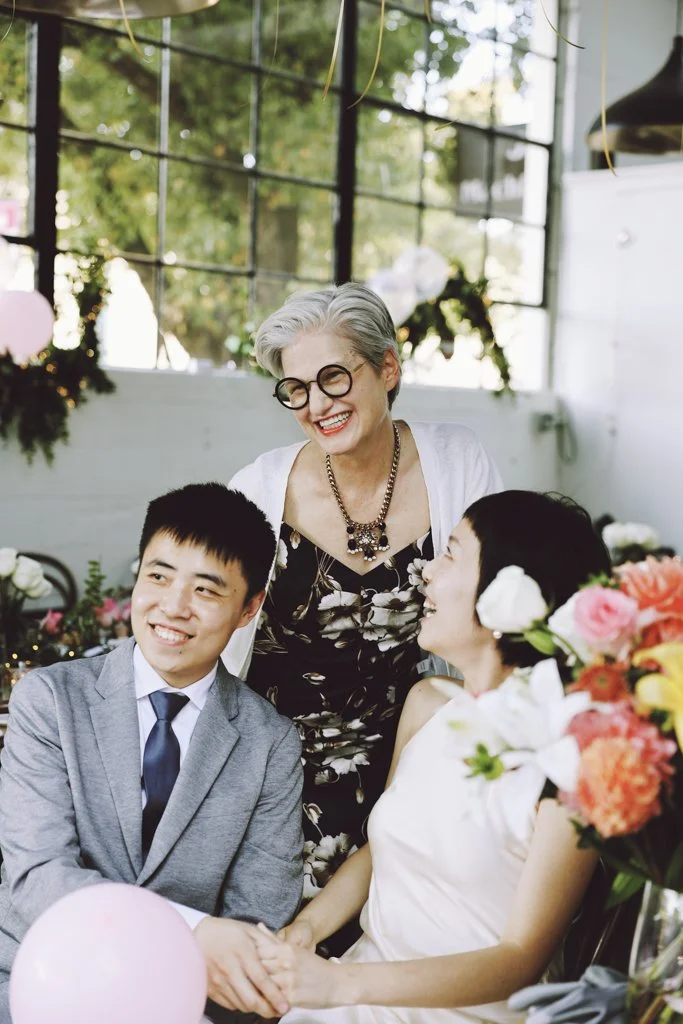A joyful group portrait of the newlyweds with their guests during an intimate wedding reception.