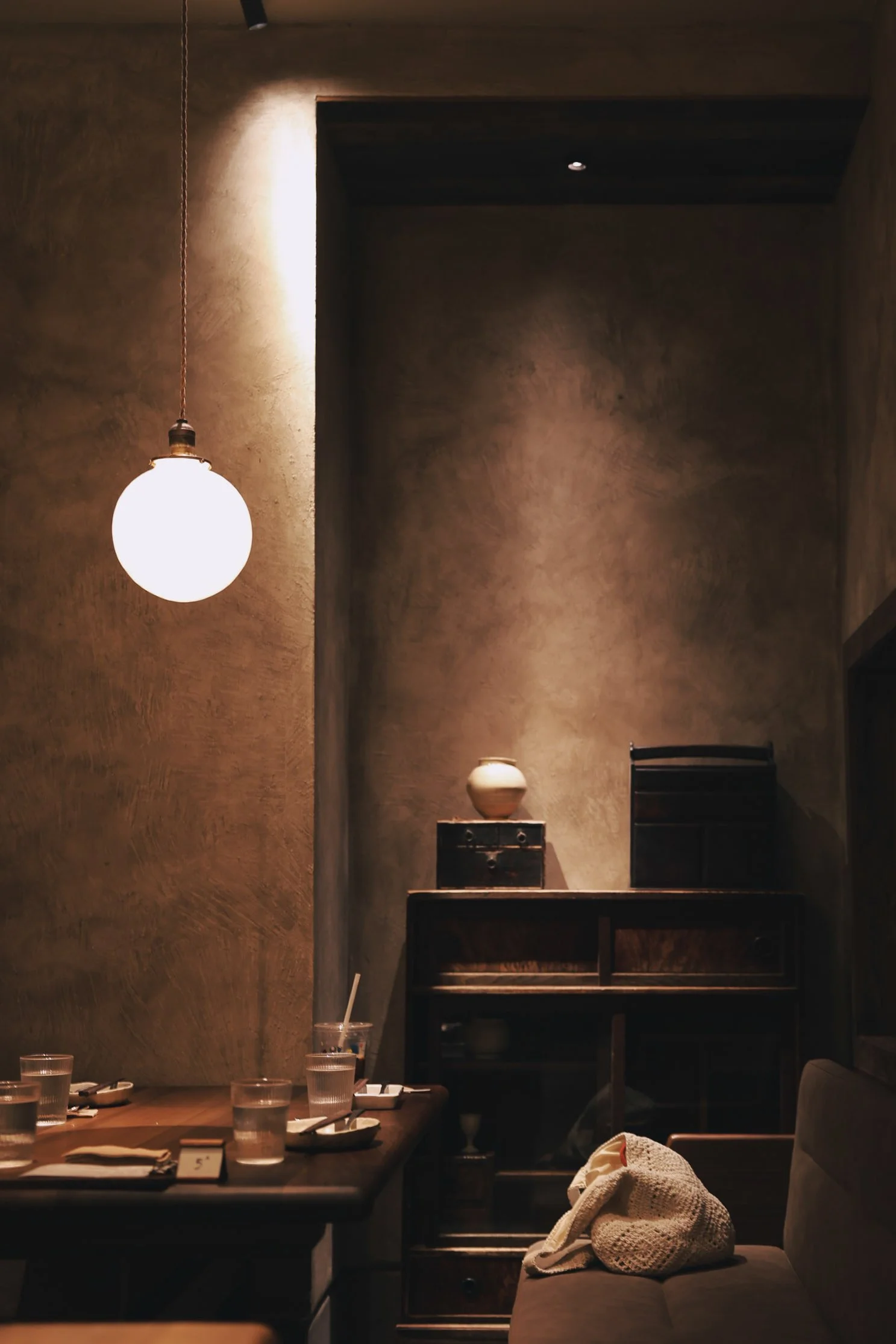 Warmly lit tea room in Hangzhou with wood furniture, textured walls, and a quiet atmosphere.