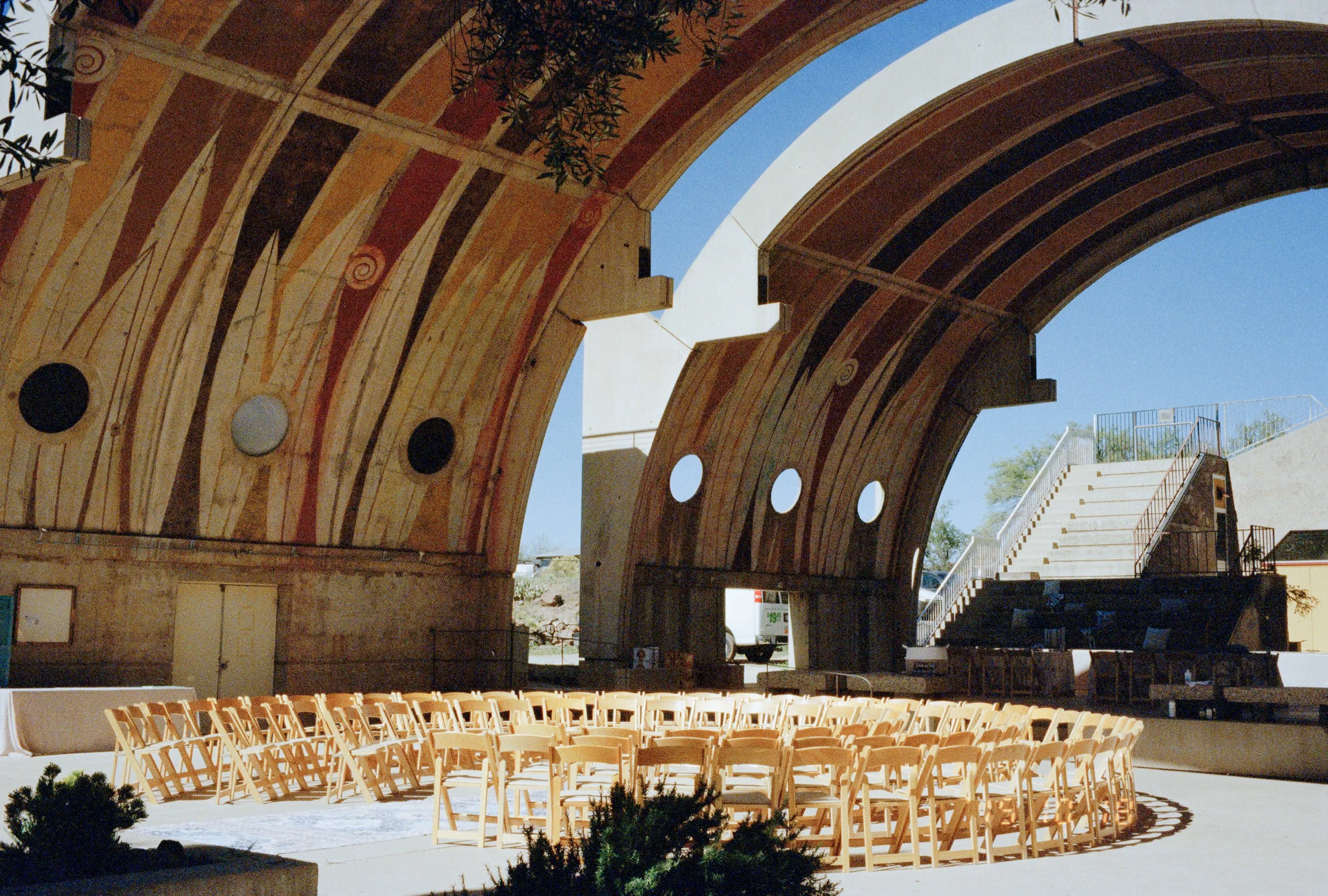Outdoor amphitheater at Arcosanti in Arizona with arched concrete structures and rows of wooden chairs.