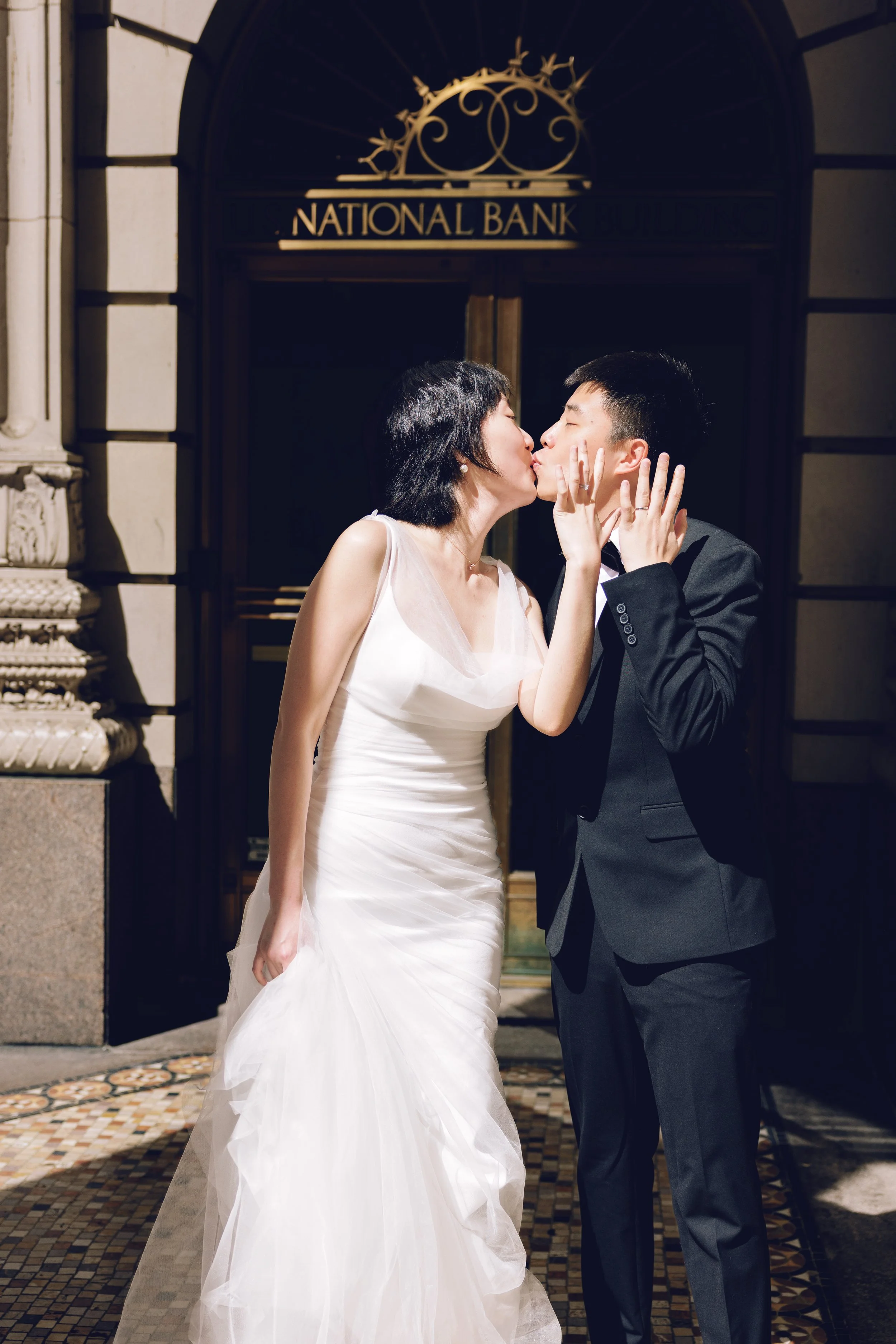 Engaged couple kissing in front of the historic United States National Bank building in downtown Portland.