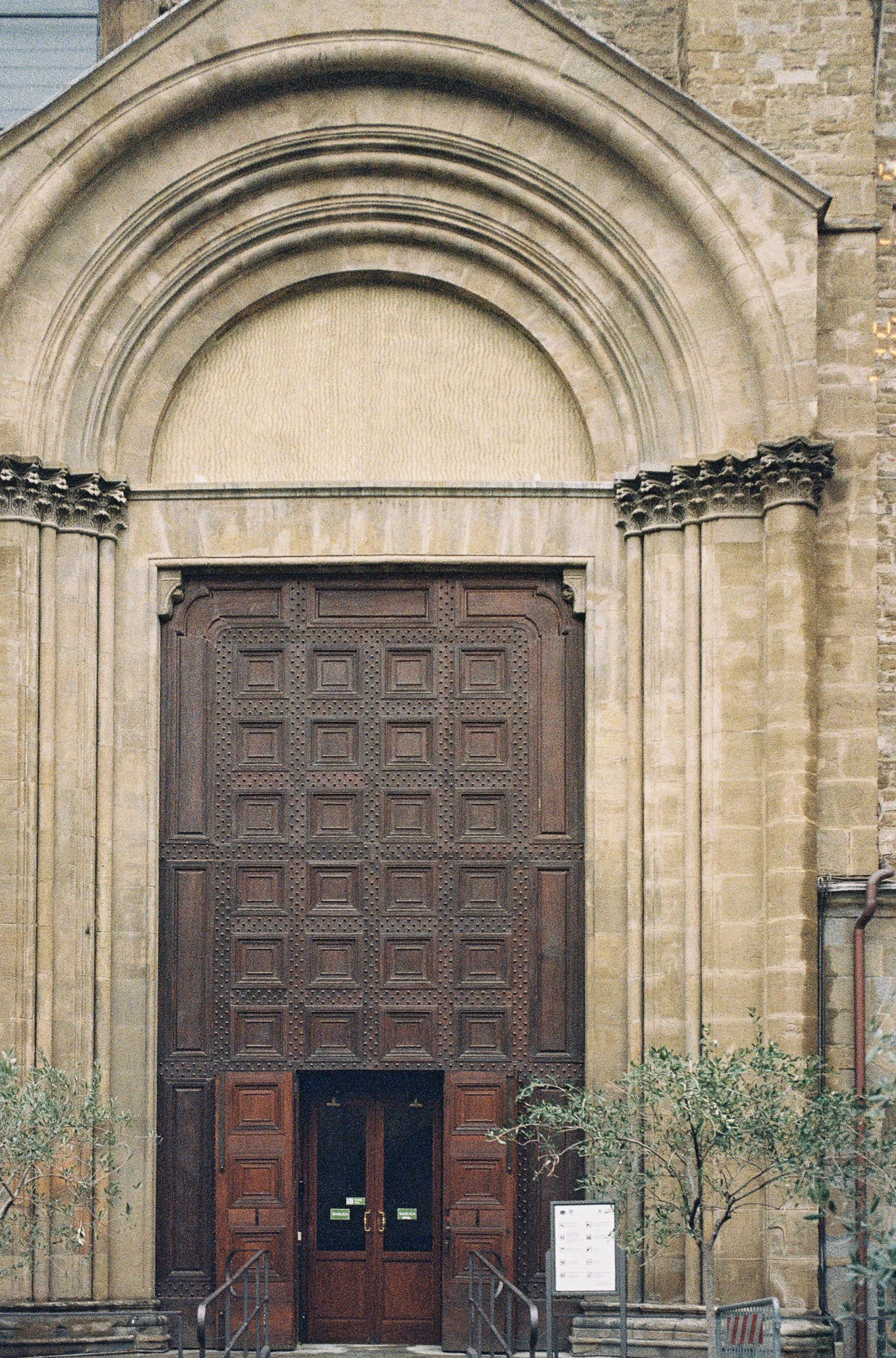 Large wooden doorway and stone architectural details on a historic building in Florence.