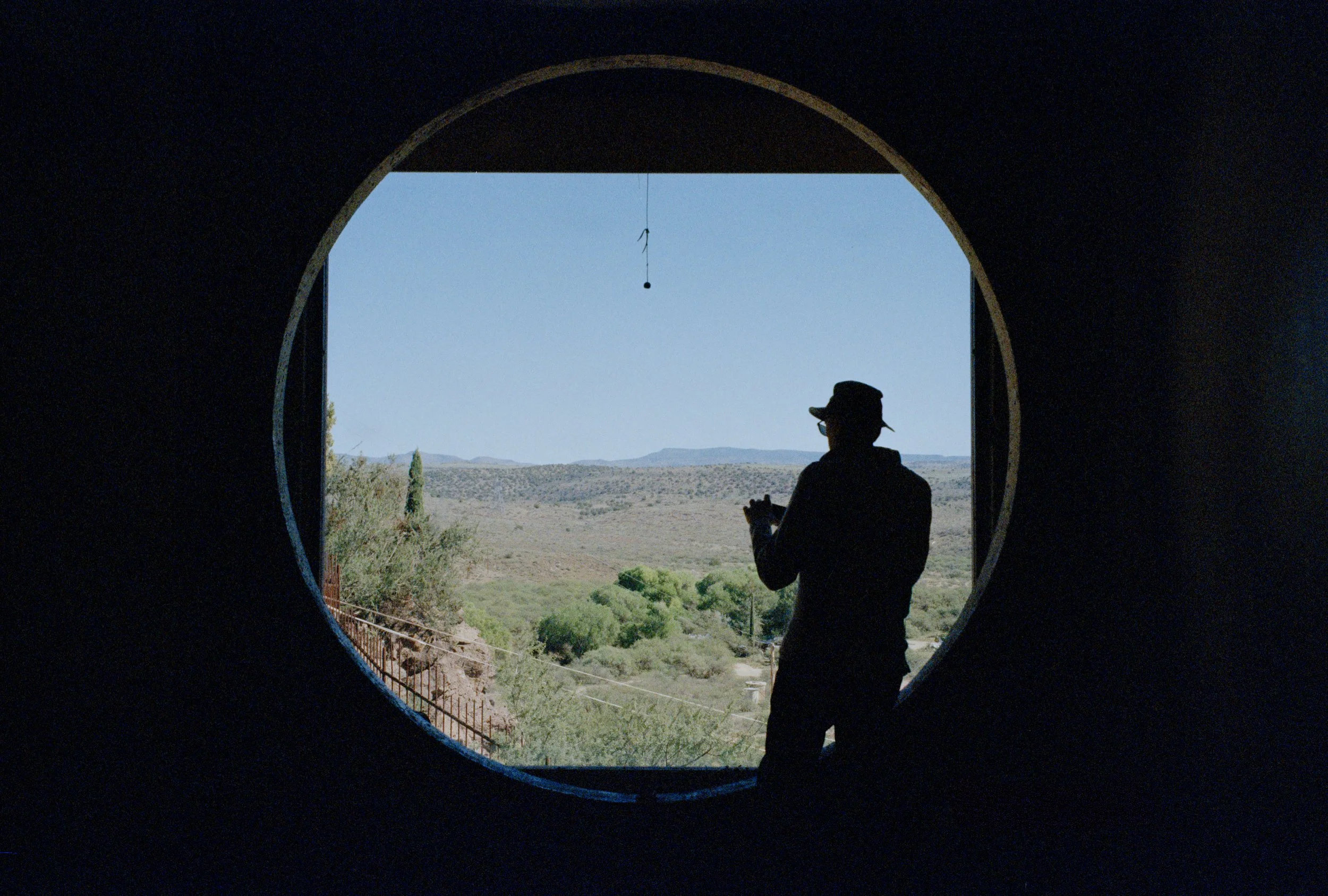 A silhouetted figure looking through a circular window at Arcosanti in Arizona.