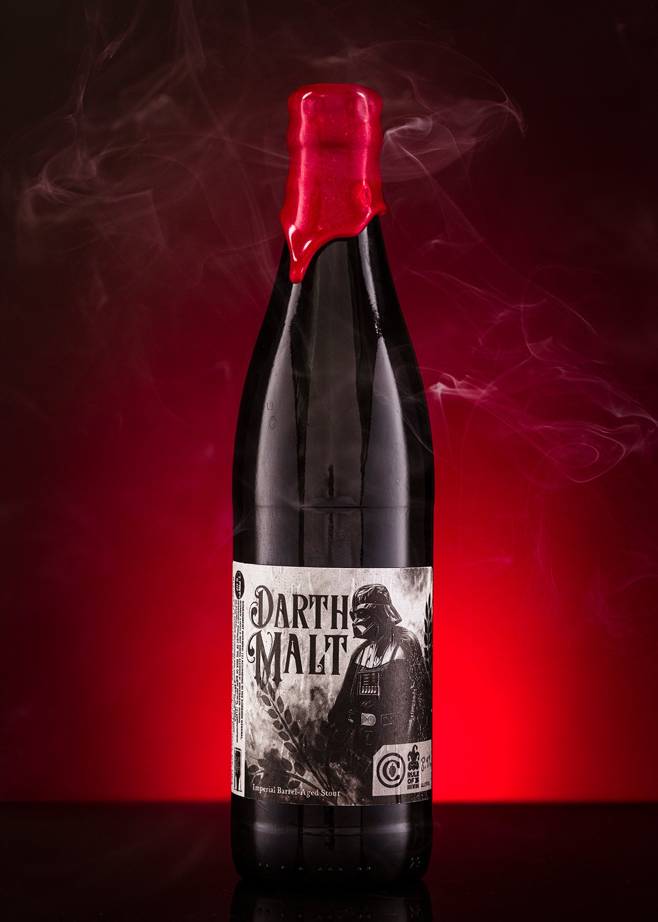 A dark bottle of Darth Malt Imperial Barrel-Aged Stout with a red wax seal on the neck, set against a red and black background with wisps of smoke.