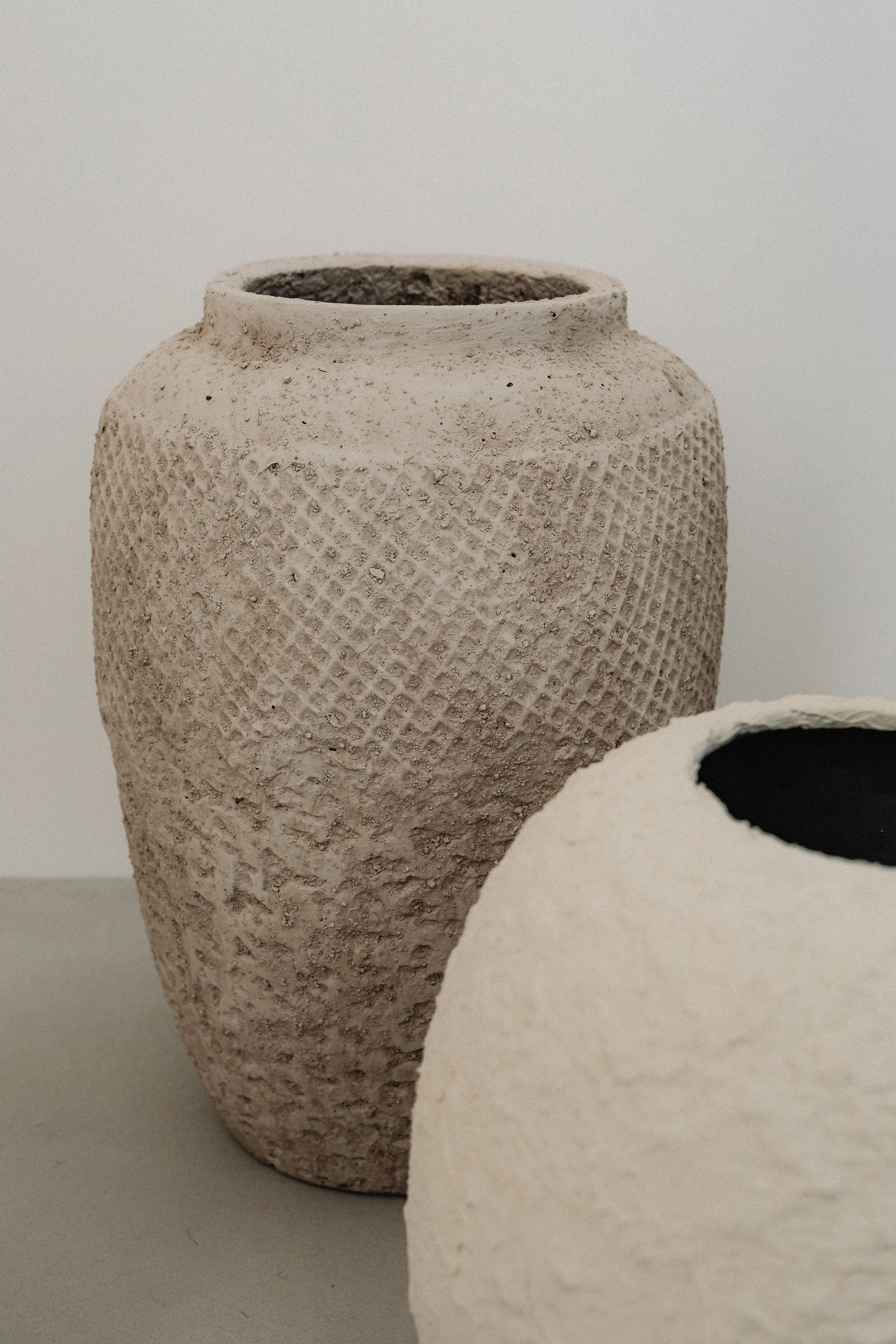 Textured beige ceramic vases with organic surface details, minimalist decor inspiration for earthy, refined interiors.