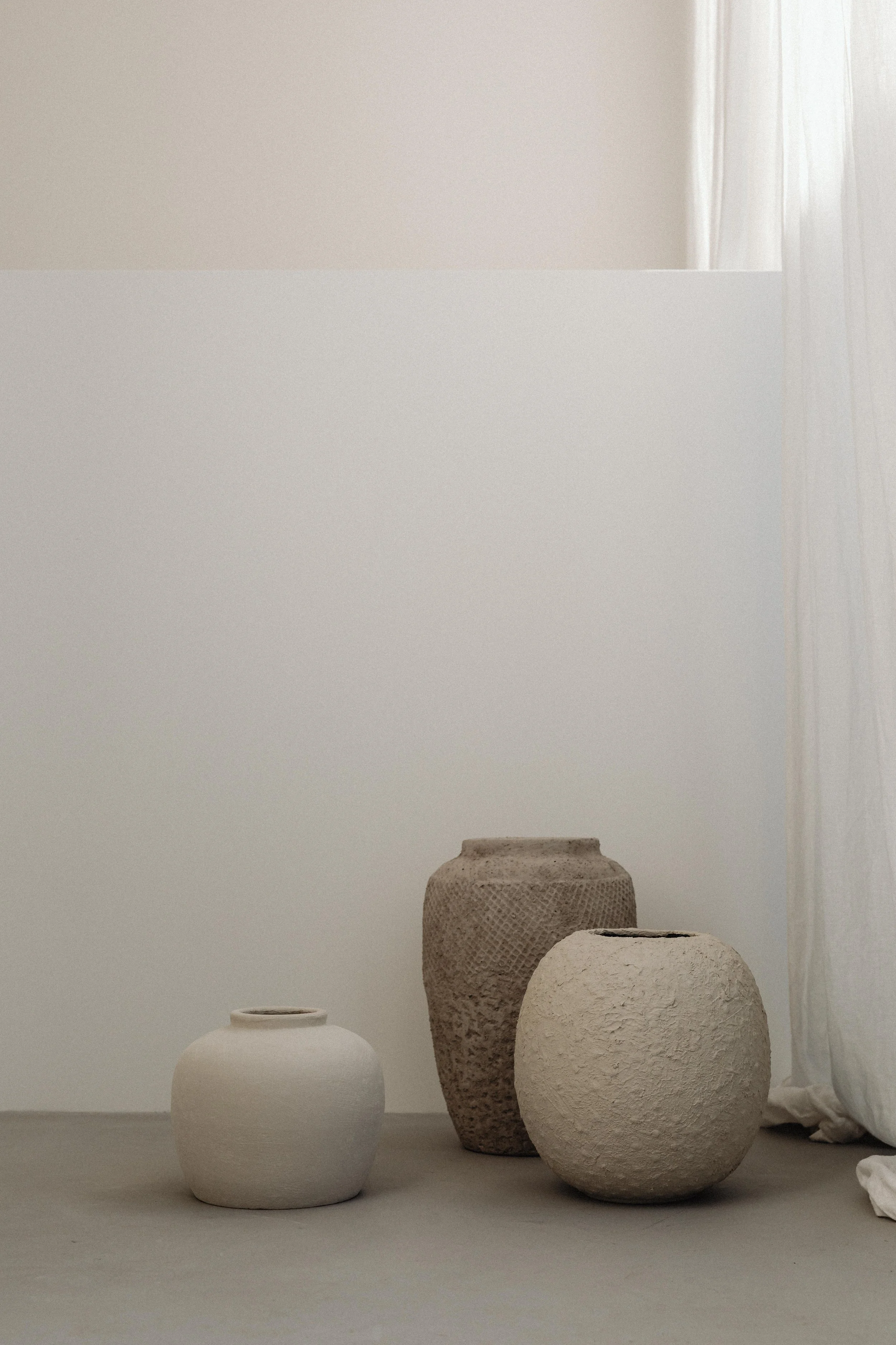 Three handmade ceramic vases in soft neutral tones, styled in a serene minimalist space for elevated lifestyle and mindful design inspiration.