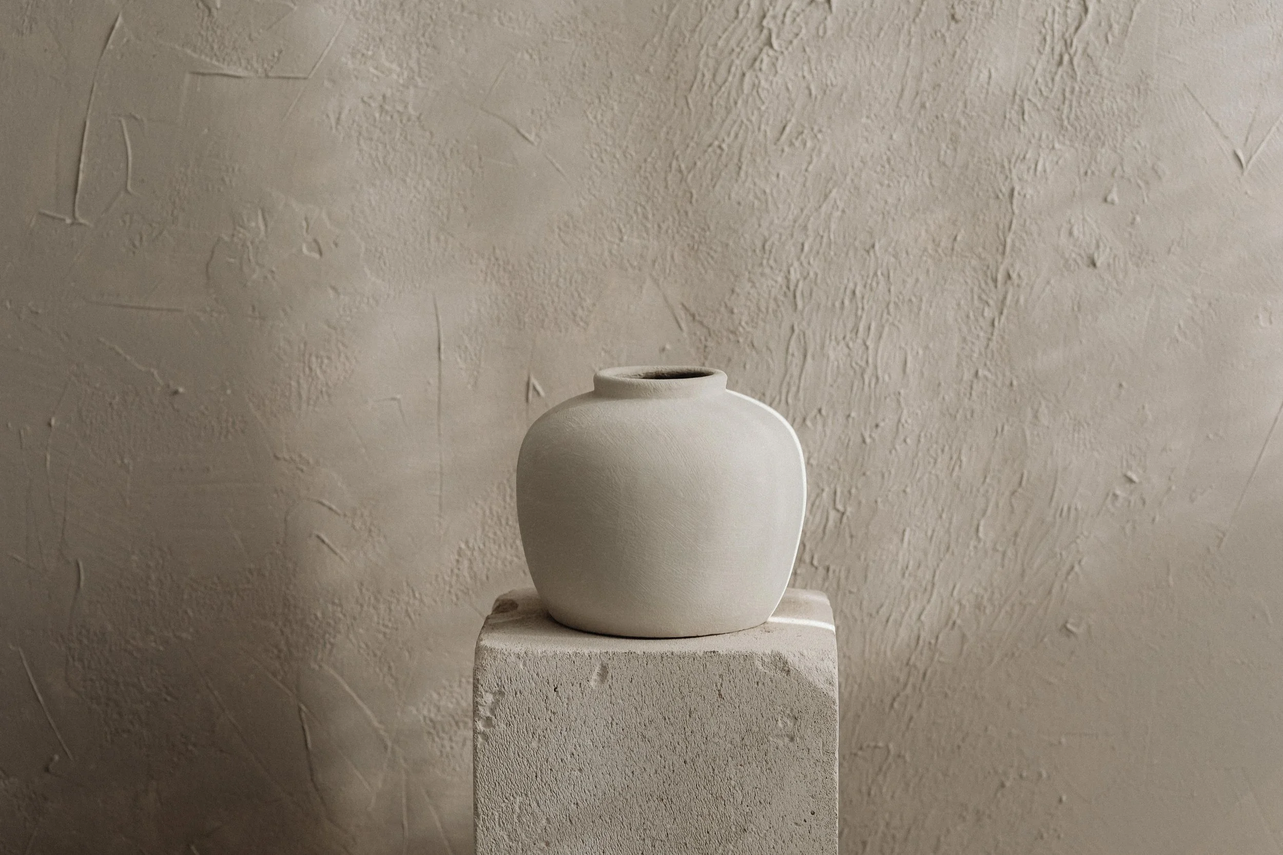 Neutral ceramic vase in a textured space, evoking clarity, stillness, and thoughtful design.