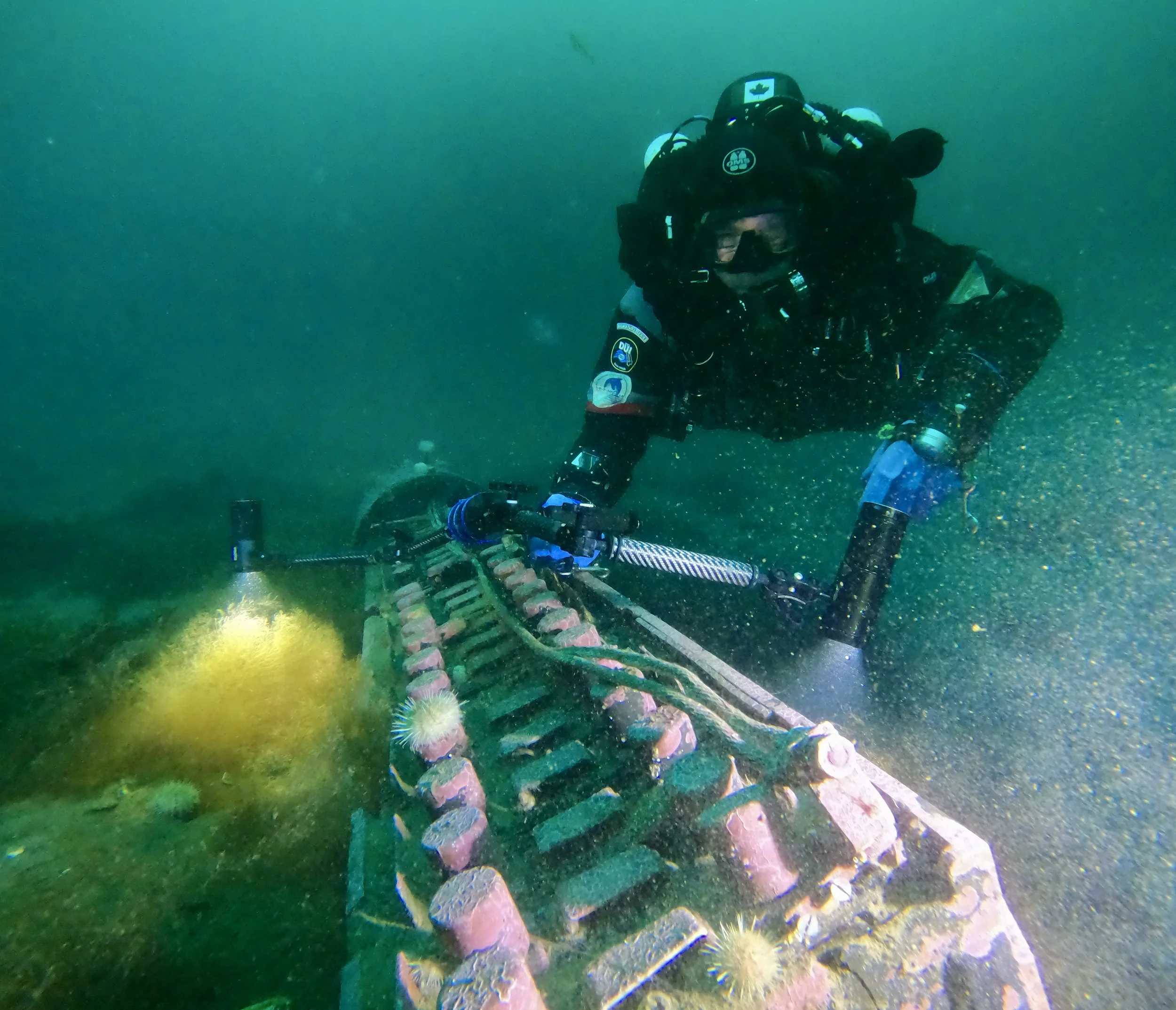 Underwater scene with a scuba diver operating a robotic device equipped with lights on a deep-sea rover or exploration robot.