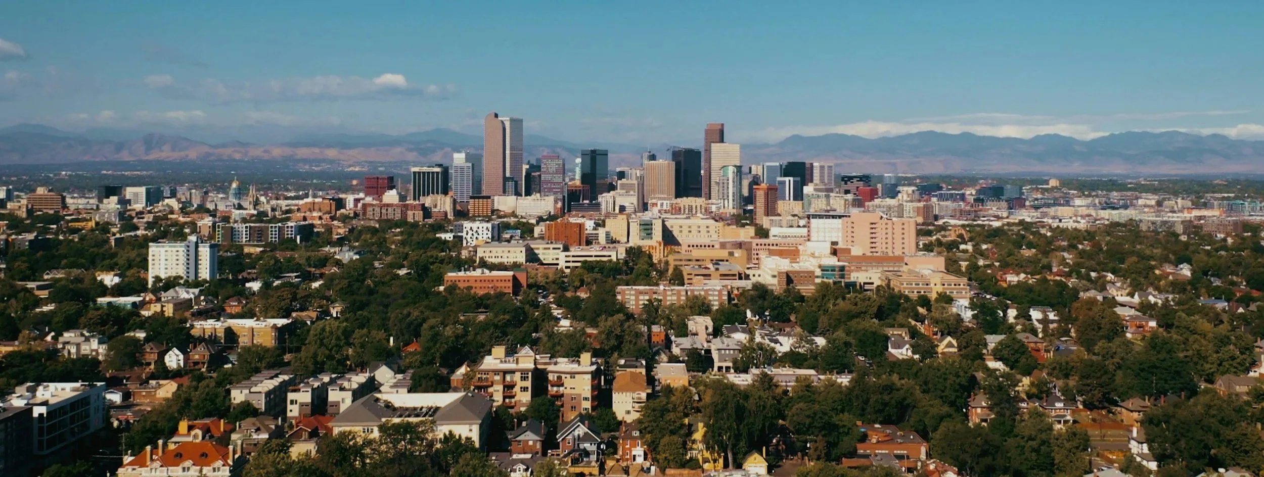 Denver, Colorado skyline above city neighborhoods with the Rocky Mountains behind
