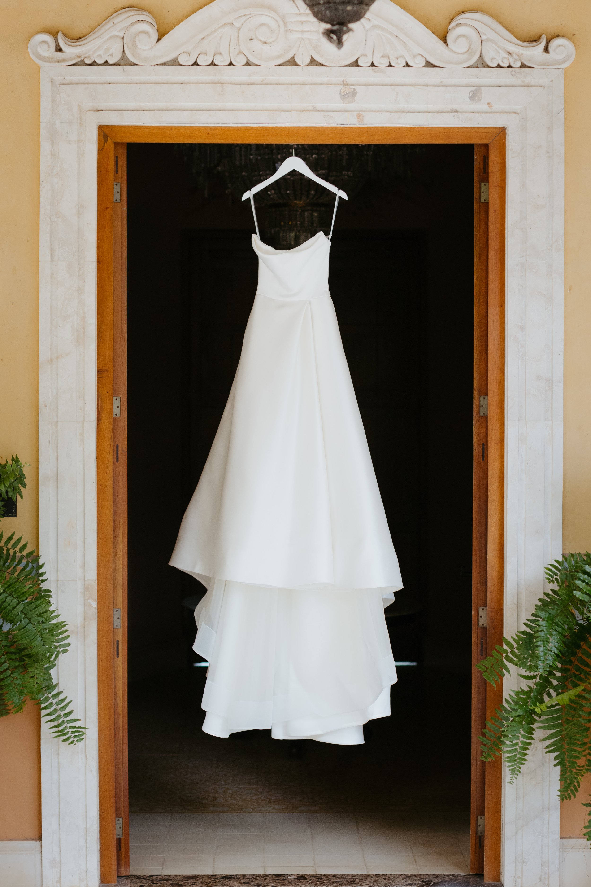 Outdoor wedding ceremony setup with white chairs, floral arrangements, and an arch against a red wooden barn background.