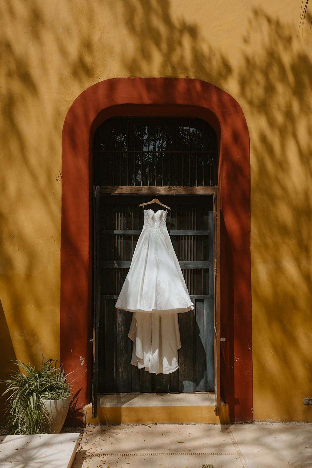 Wedding reception table with a tiered wedding cake featuring a bride and groom figurine on top, surrounded by pink and purple flowers, wine glasses, plates, a silver cake knife, and a calendar.