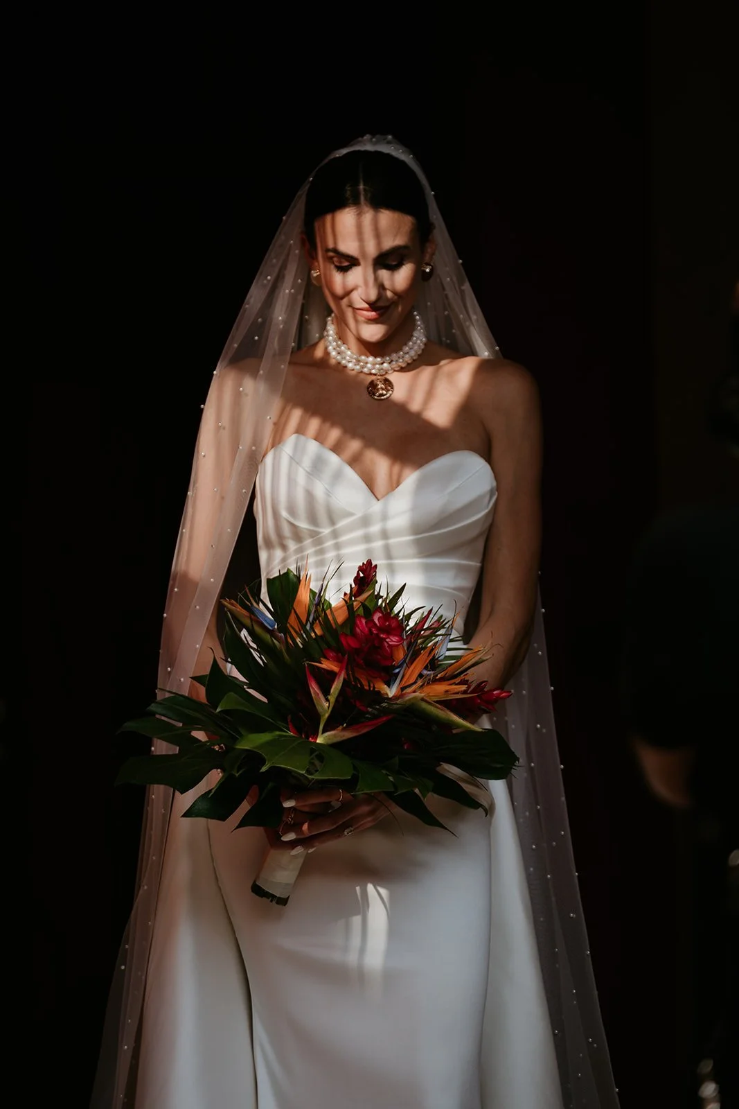 Outdoor wedding ceremony setup with white chairs, floral arrangements, and an arch against a red wooden barn background.