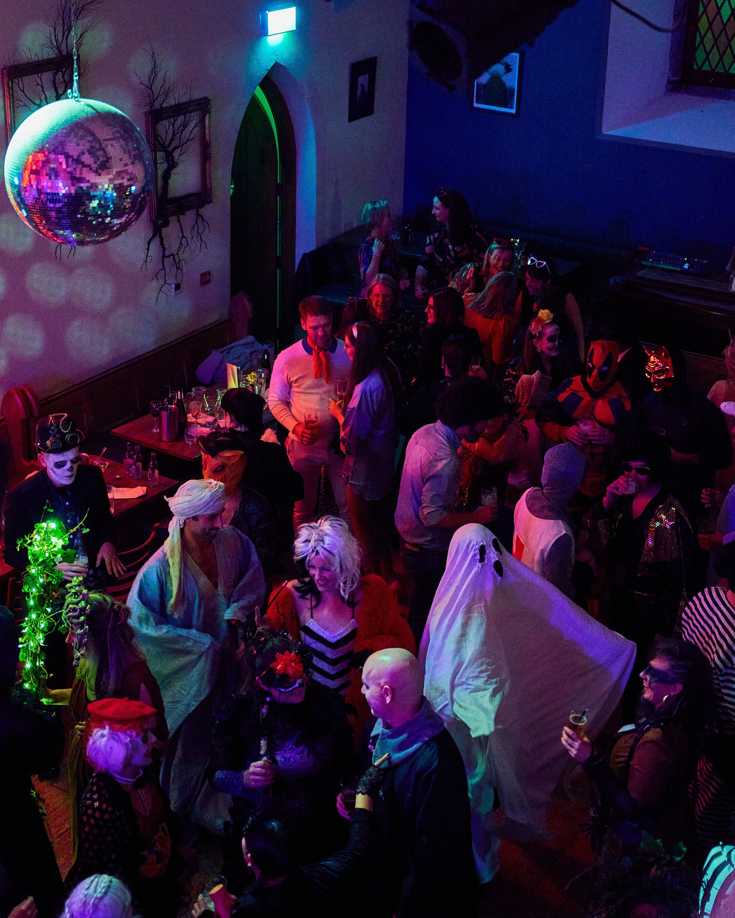 Costume and fancy dress ball, Divil's Disco at 10 Bridge Street. An Feile Eile, Killorglin, Co Kerry.
People at a costume party with various costumes, masks, and a large disco ball, in a dimly lit room.