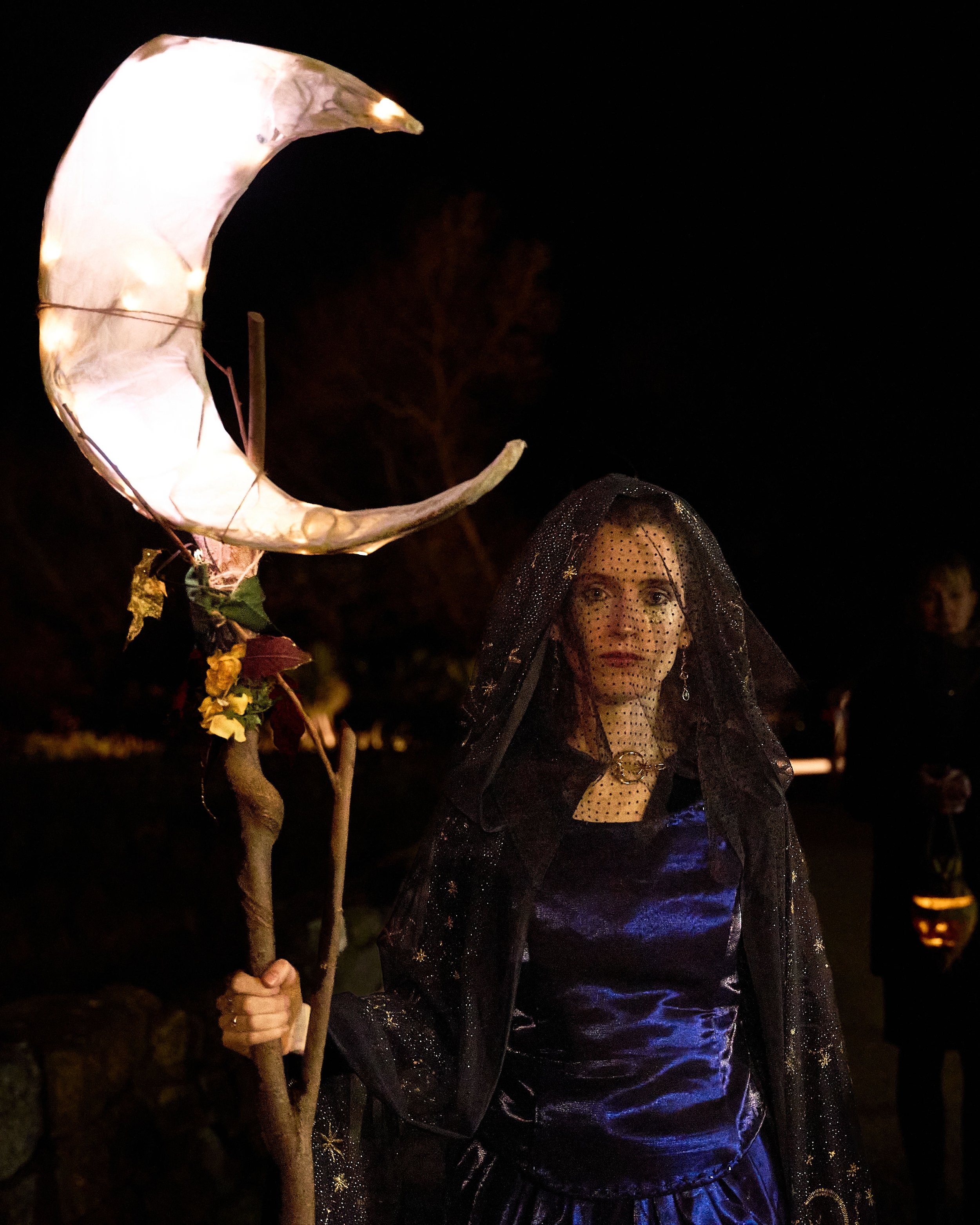 Woman dressed as a witch holding a crescent moon lantern at night
Ancestral Effigy made by Phil McSweeney of Tralee, in the procession on Halloween night. Grilse Gallery in Killorglin, Co Kerry. An Feile Eile, Halloween Festival