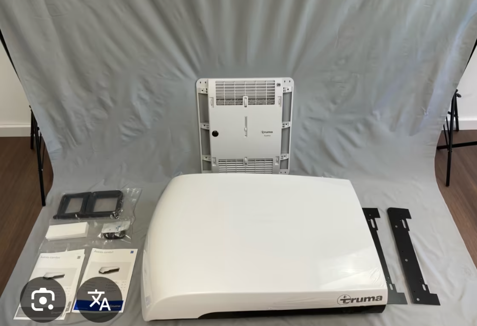 Baugruppe eines alten Luftentfeuchters oder Klimageräts mit abgenommenen Teilen auf einer weißen Oberfläche, inklusive Bedienfeld, Gehäuseteile, Anleitungen und Montageschienen.