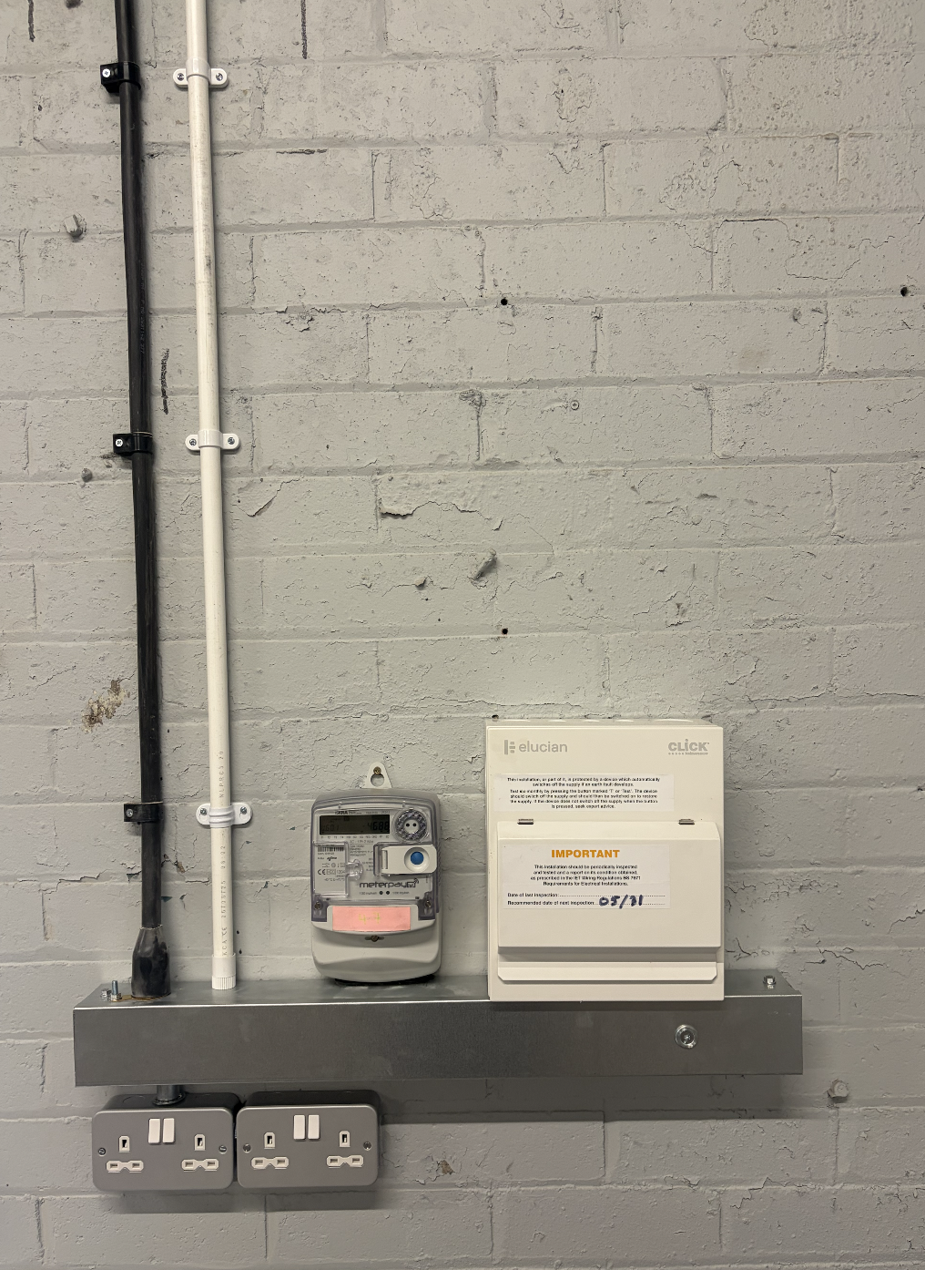 Electrical utility installation on a gray wall, including a digital meter, circuit breakers, and an alert message box.
