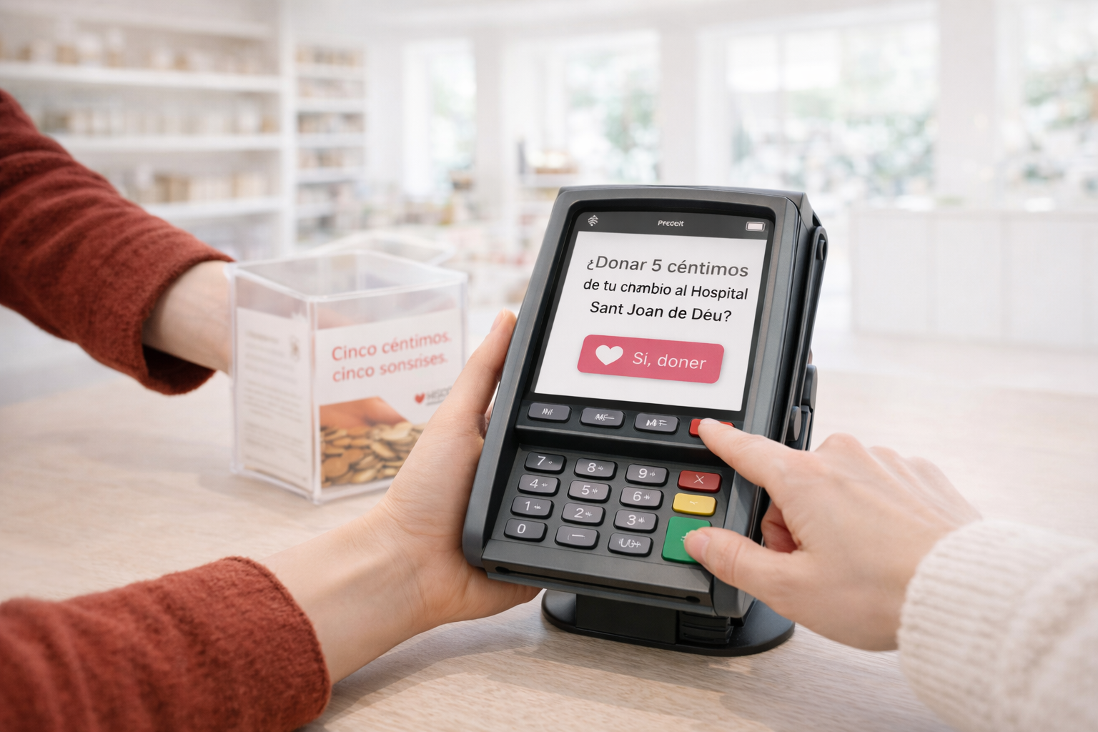 Person using a payment terminal to donate five cents to Sant Joan de Déu Hospital, with a donation box of coins in the background.