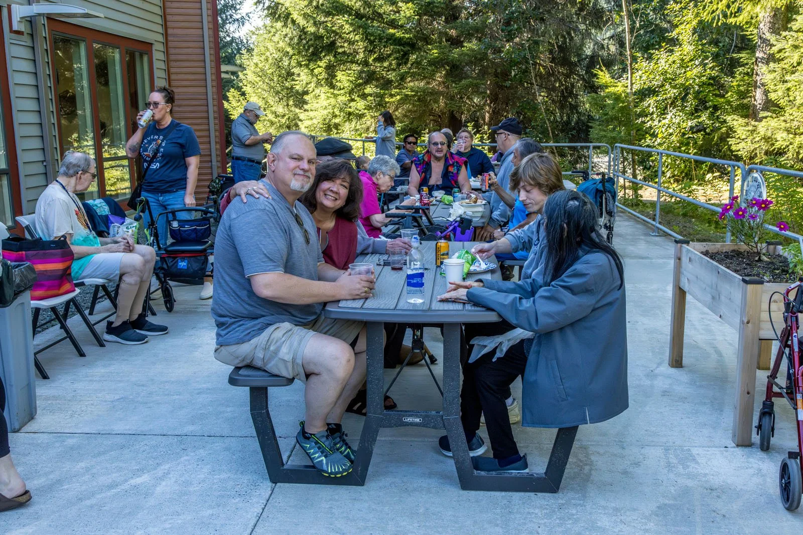 Residents and visitors gathered outdoors at a picnic table enjoying food and drinks at the Labor Day picnic at Riverview Senior Living and Memory Care in Juneau Alaska