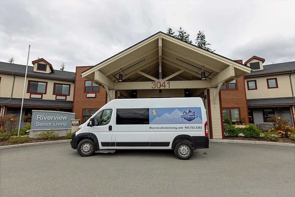 White service van with Riverview Senior Living logo parked outside a senior living facility at 3041 Riverview Senior Living.