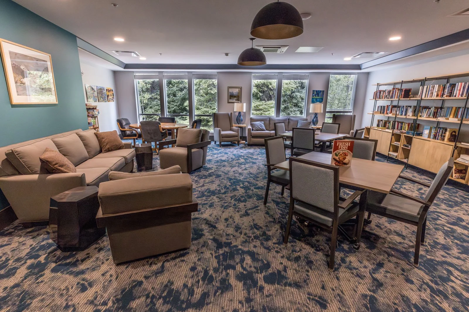 A spacious lounge area with sofas, armchairs, and tables at Riverview Senior Living and Memory Care in Juneau Alaska