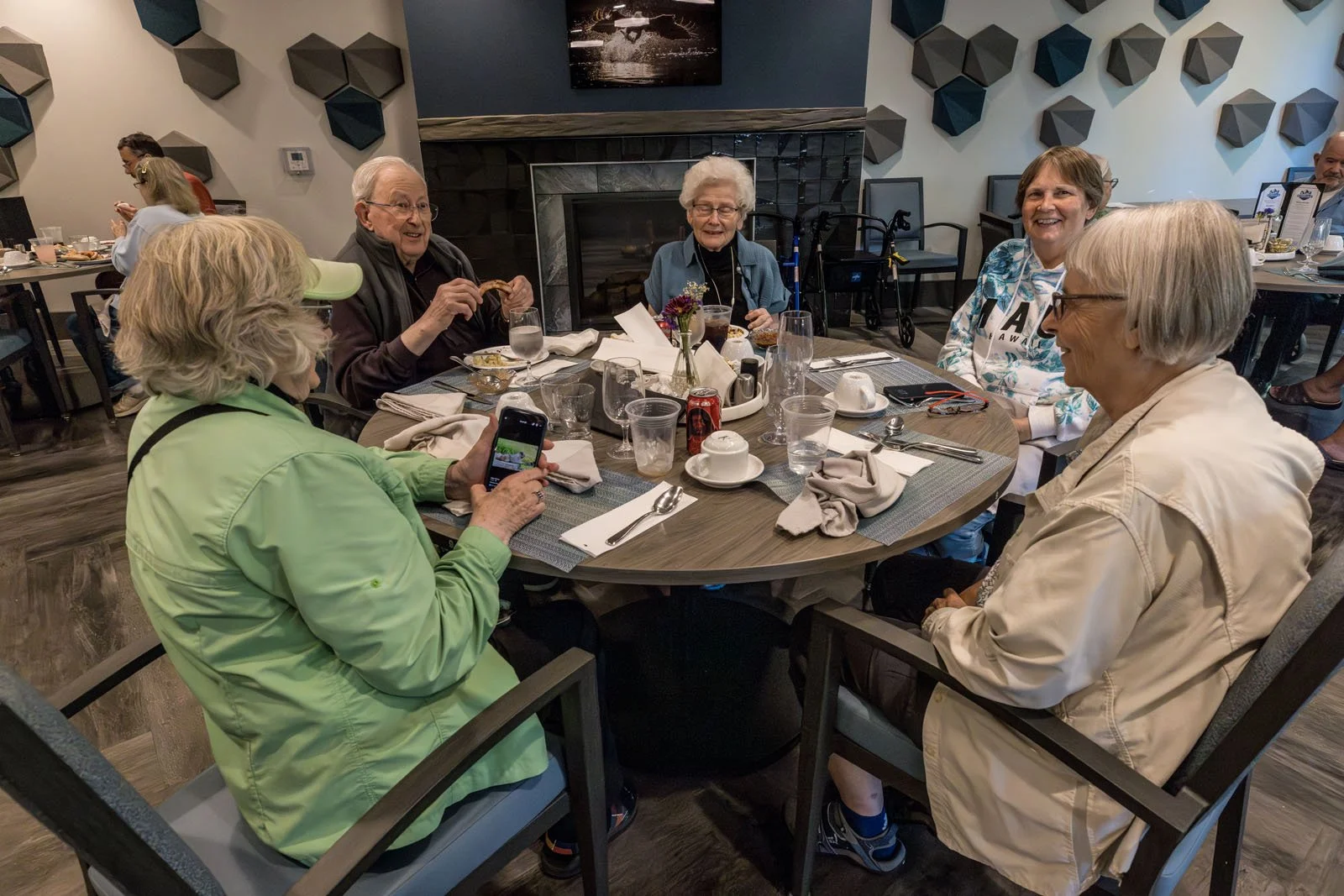 Residents and visitors sitting around a dining table at Riverview Senior Living and Memory Care in Juneau Alaska, enjoying a meal and conversation