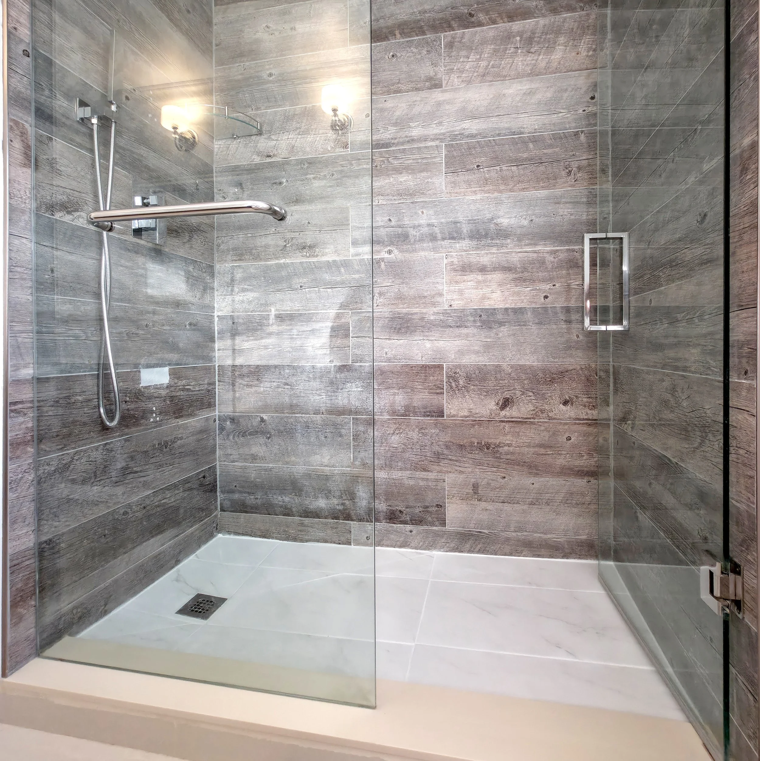 Renovated walk-in shower featuring porcelain wall tiles, a sleek glass enclosure, and a new white porcelain floor installed by Pam Arc Inc. in Richmond Hill, Ontario.