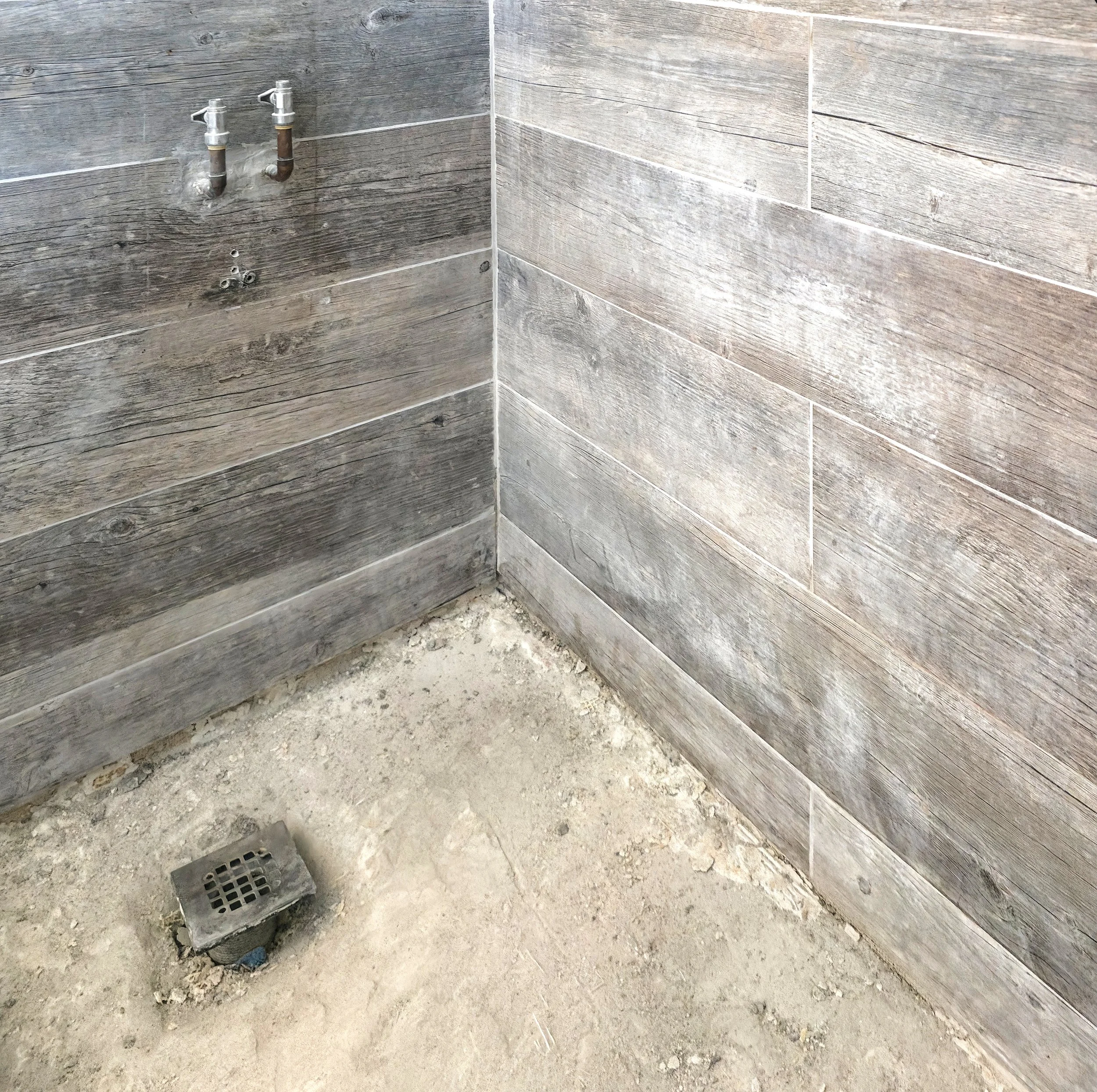Bathroom Renovation in Richmond Hill, Ontario with demolished shower floor, exposing the sub-base and drain