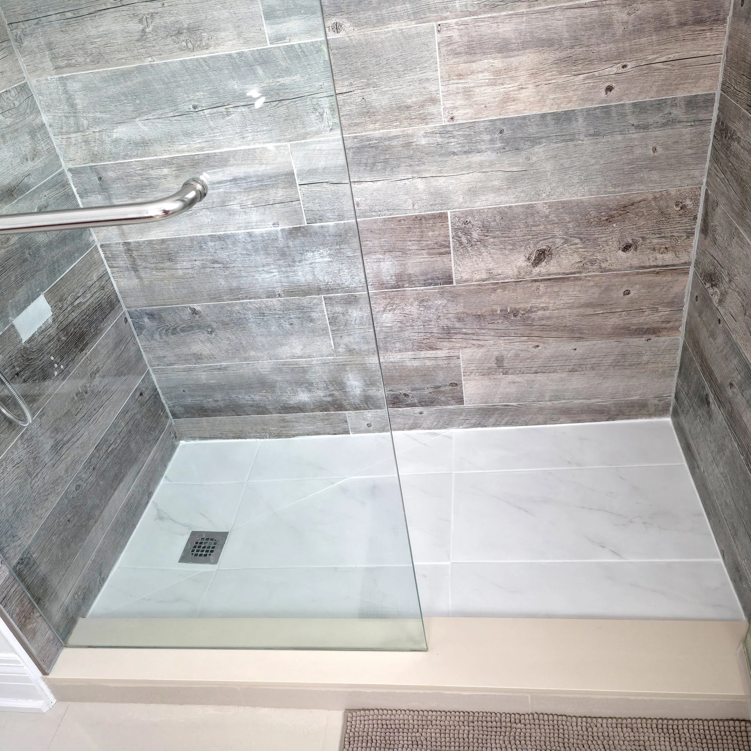 Bathroom renovation in Richmond Hill, Ontario showing the new porcelain shower floor with modern glass enclosure and wood-look porcelain wall tiles installed by Pam Arc Inc.