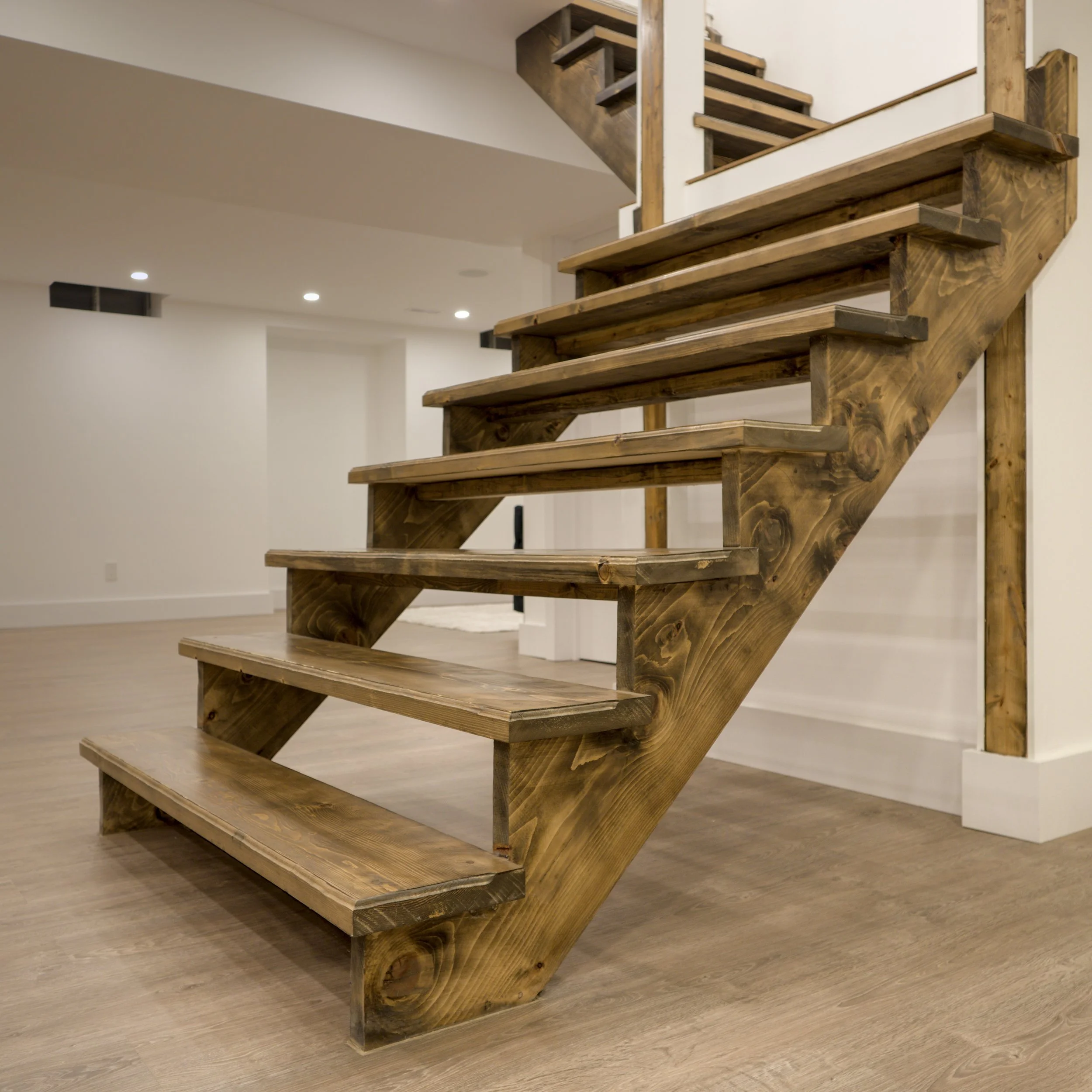 Modern open-riser basement staircase with wide stained pine steps in Richmond Hill renovation
