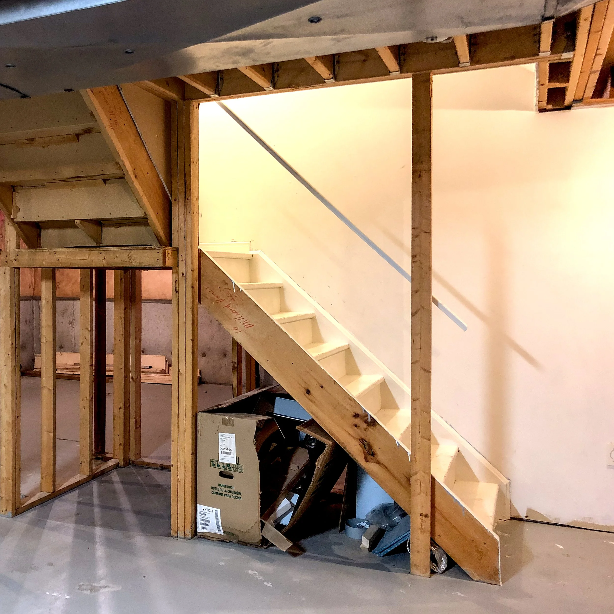 Side biew of unfinished basement staircase with exposed framing and closed-in design