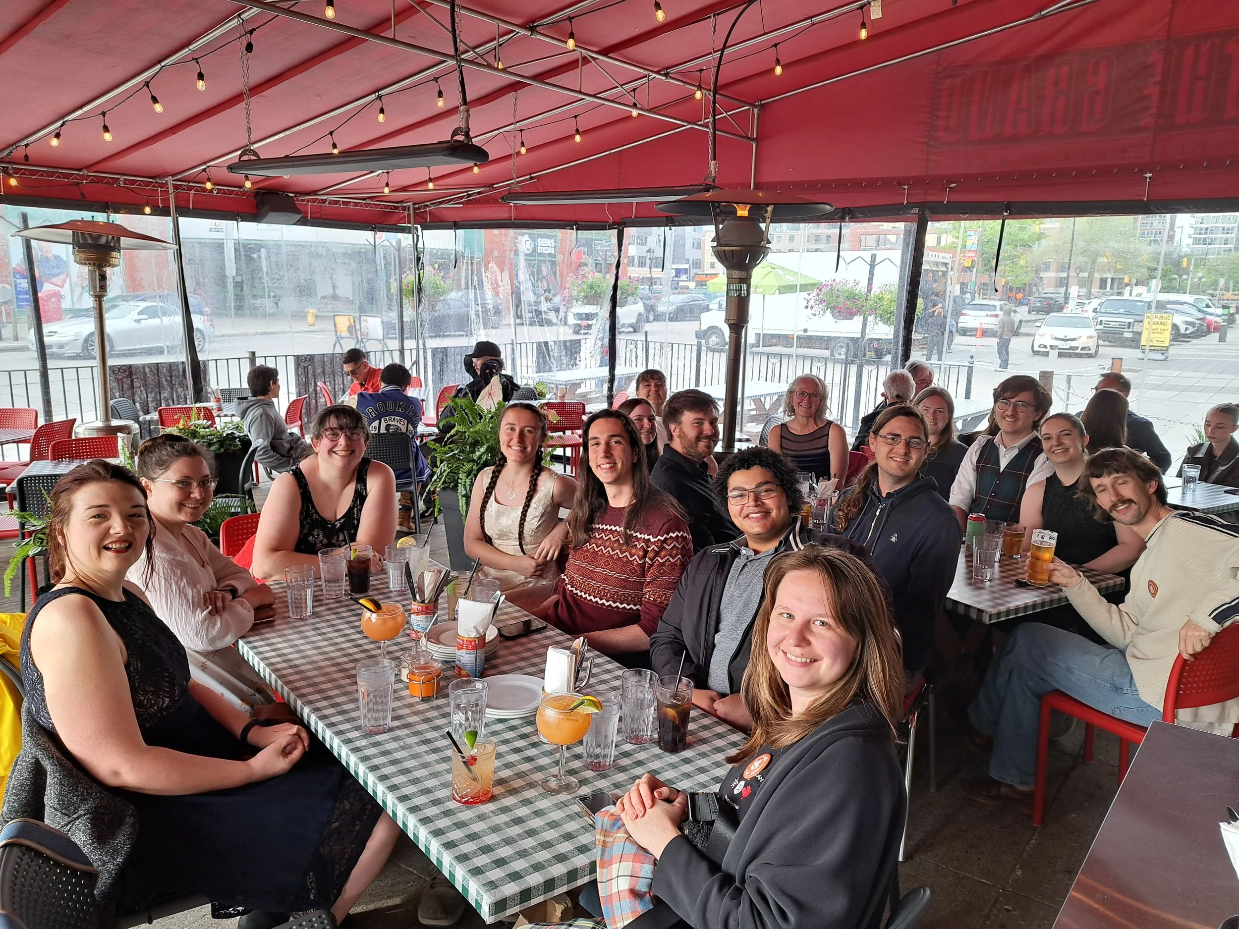 Young people gathered for a meal under a canopy at an outdoor cafe