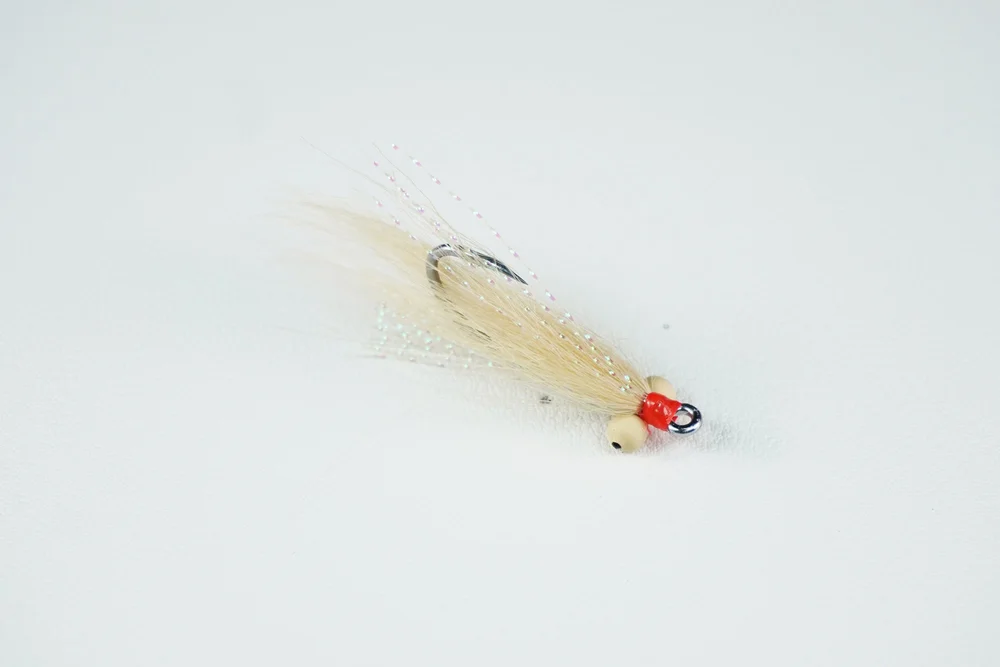 Megafin Gotcha Shallow bonefish fly, tan wing and orange head, with bead-chain eyes, seen from the side.