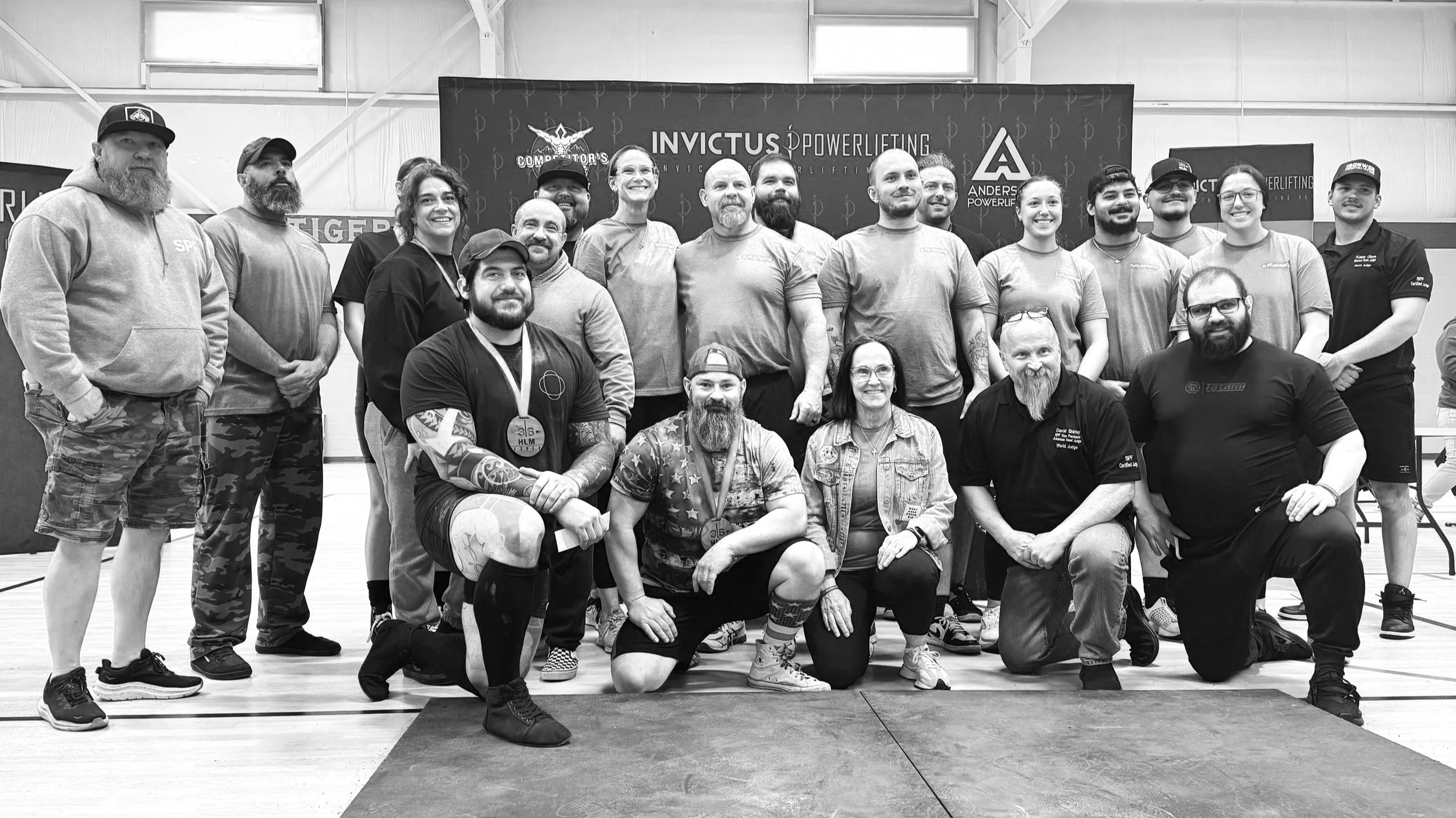Group of people in a gym posing for a photo, some wearing medals.