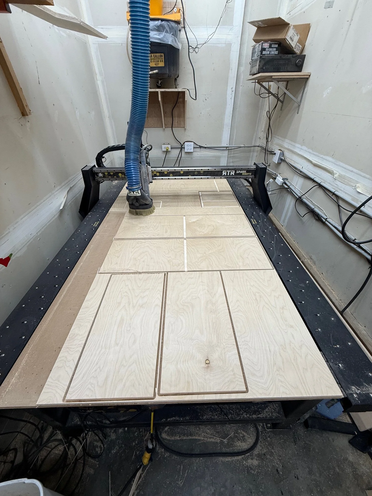 A robotic device working on a tiled floor in a room under construction, with tools and wiring visible.