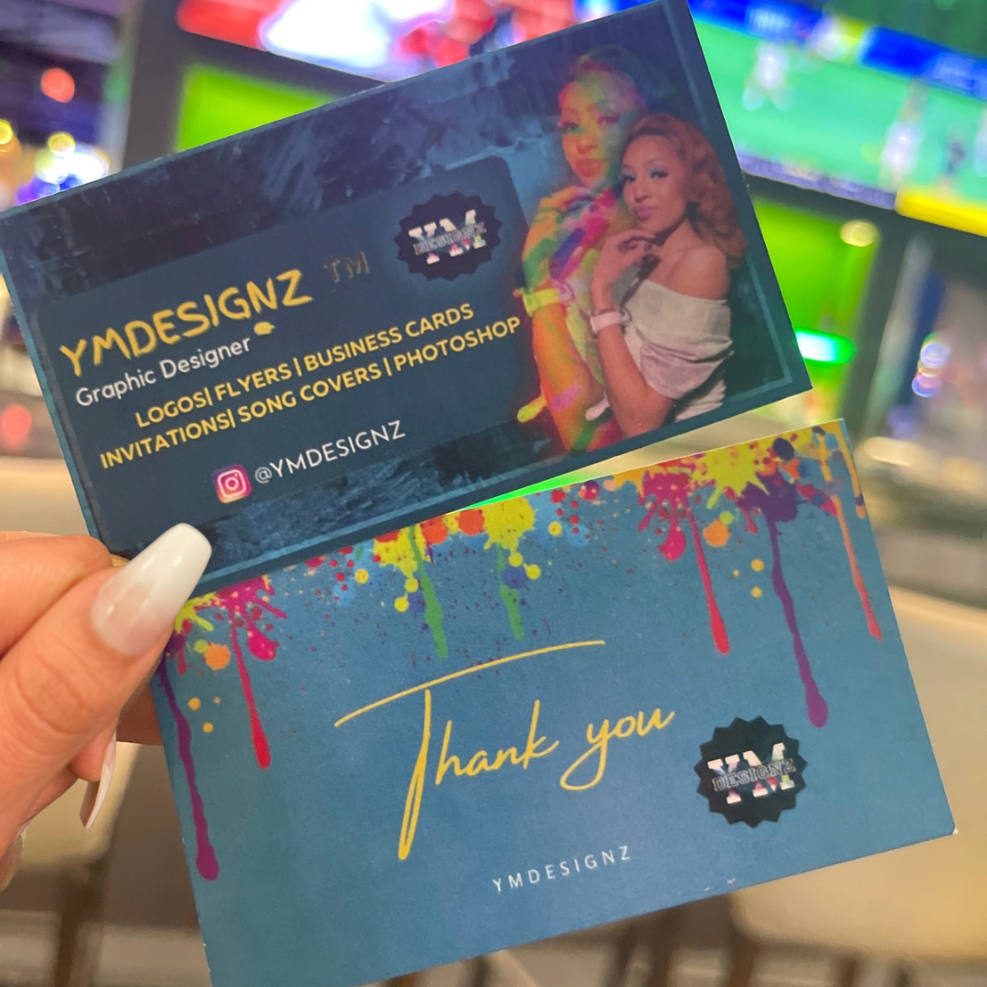 Business card and thank you card for YMDesignZ, a graphic designer service, held in front of a colorful background. The business card features images of two women, contact information, and list of services including logos, flyers, business cards, invitations, song covers, and Photoshop.