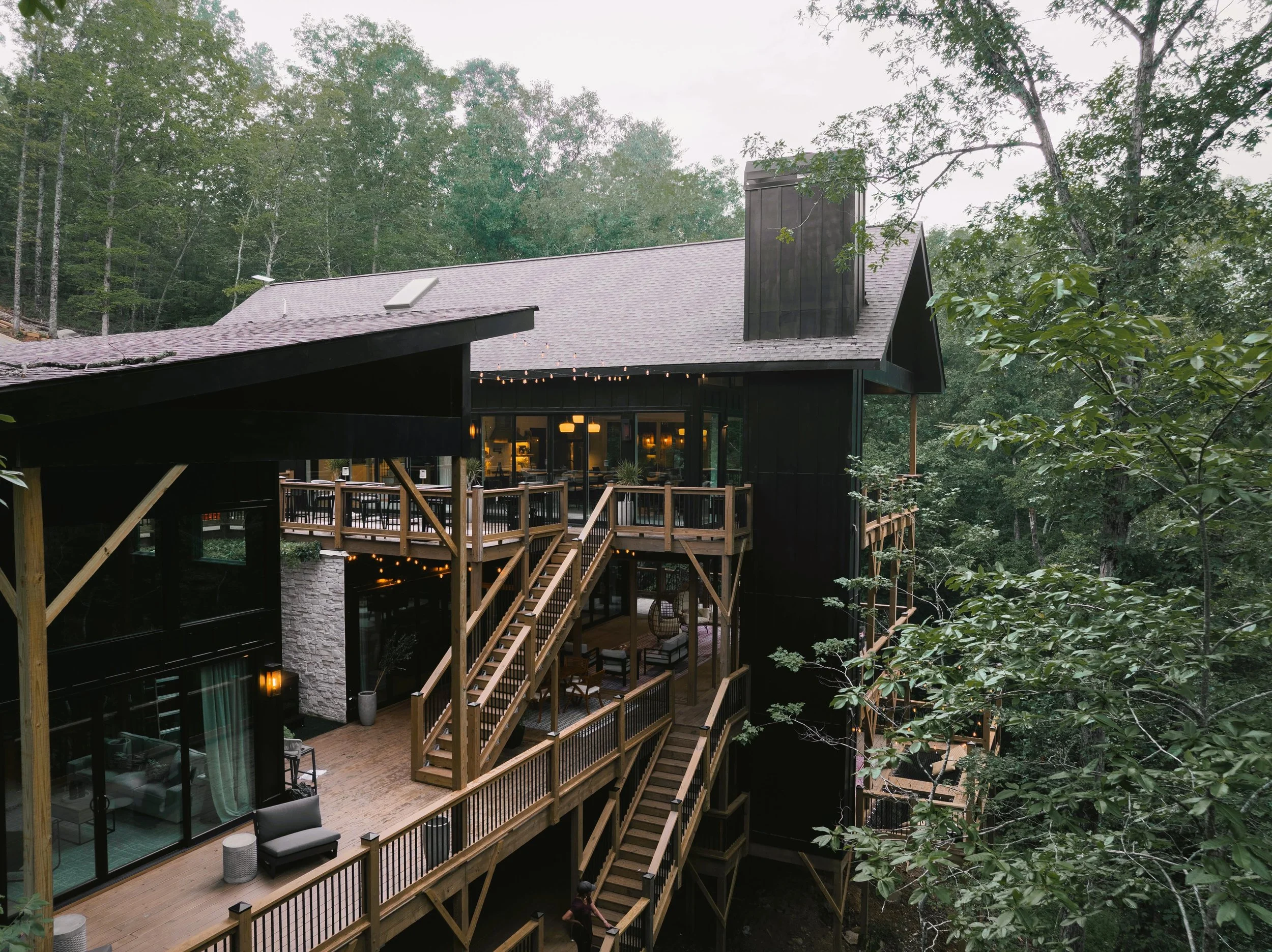 Multi-story house with wooden decks surrounded by trees in a forested area.