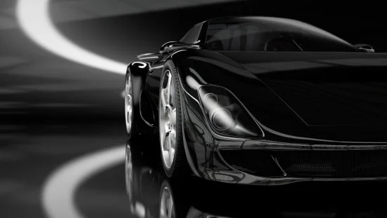 A sleek black sports car in a dark setting with light streaks reflecting off its surface.