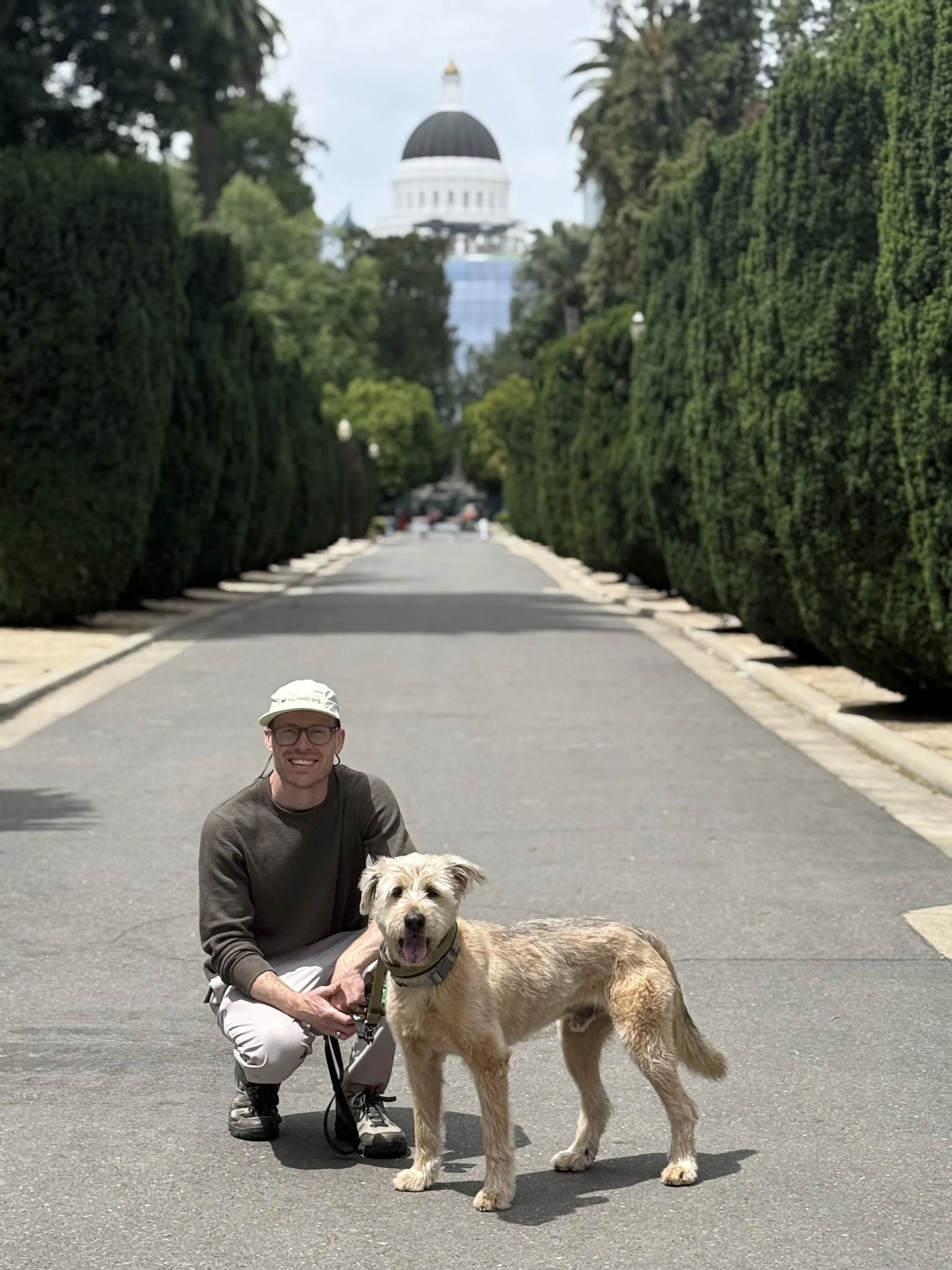 A man and his yellow mold dog in front of the Sacramento state capital building