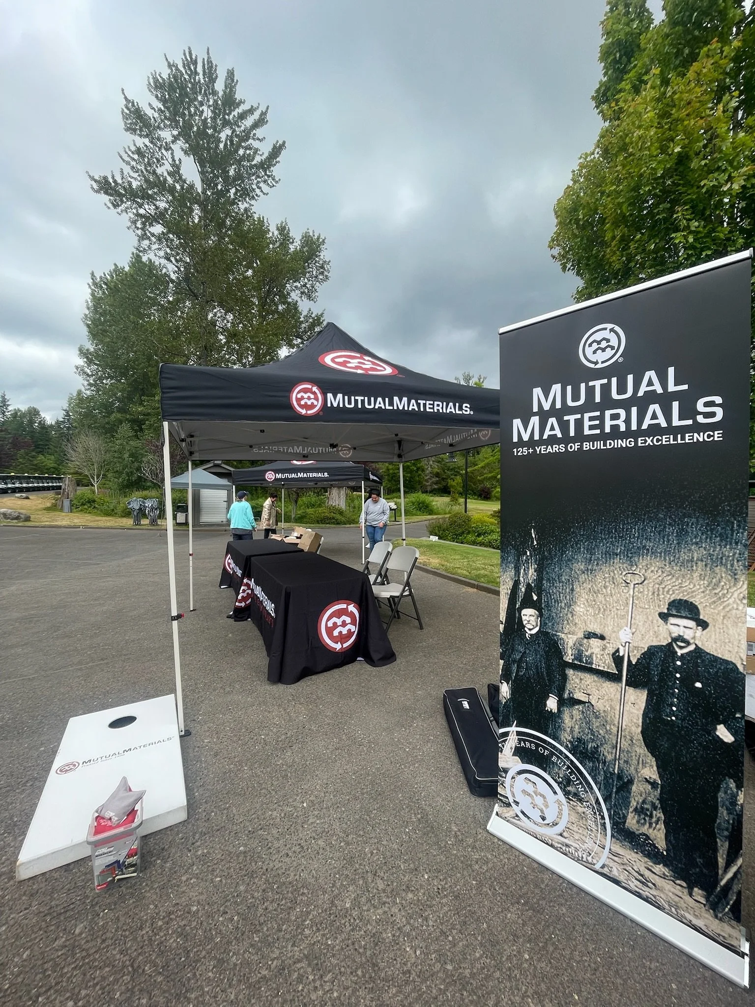 Early stages of the event setup featuring the branded cornhole game and retractable banner.