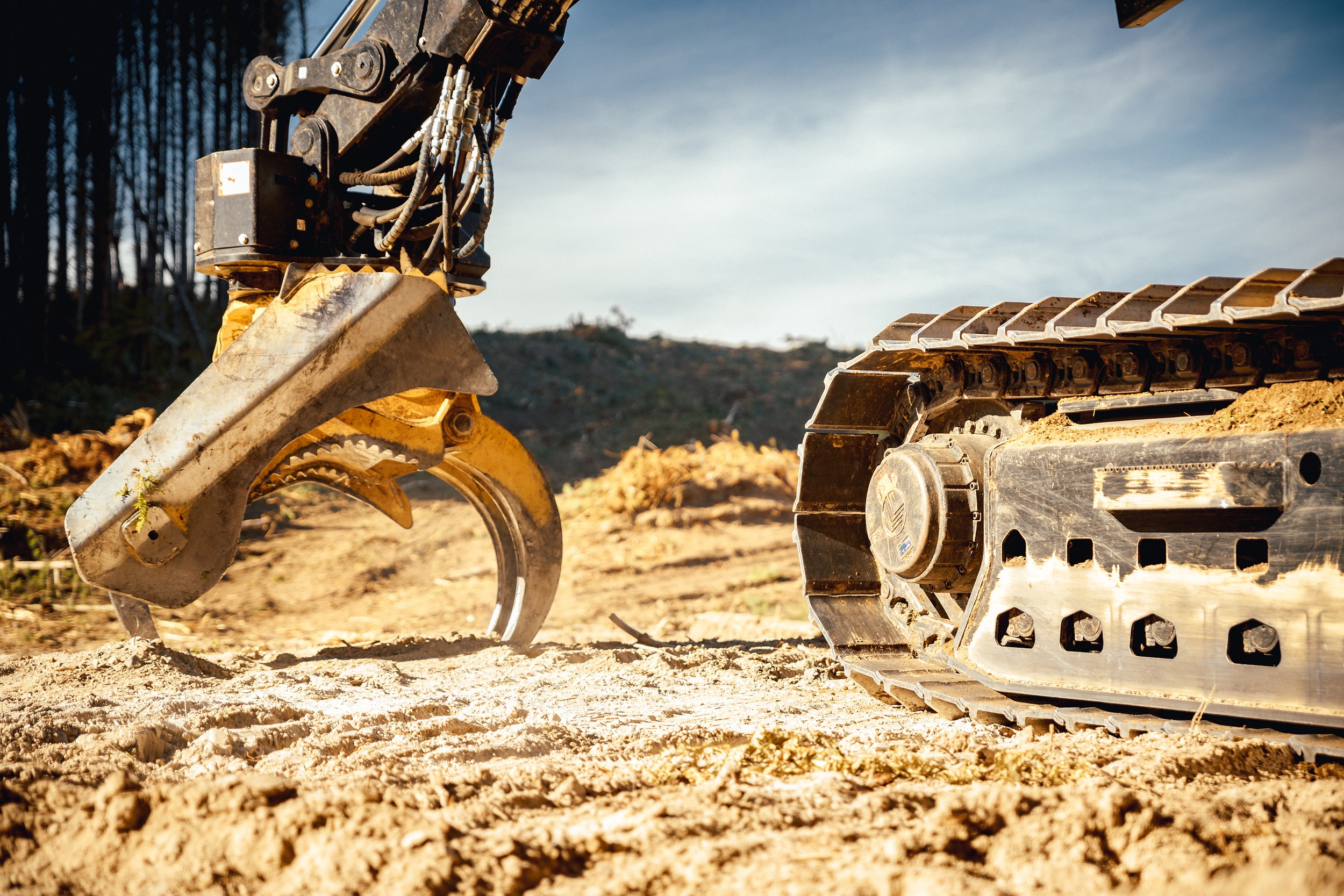 Close-up of a tracked excavator and a bulldozer on dirt at a construction site.