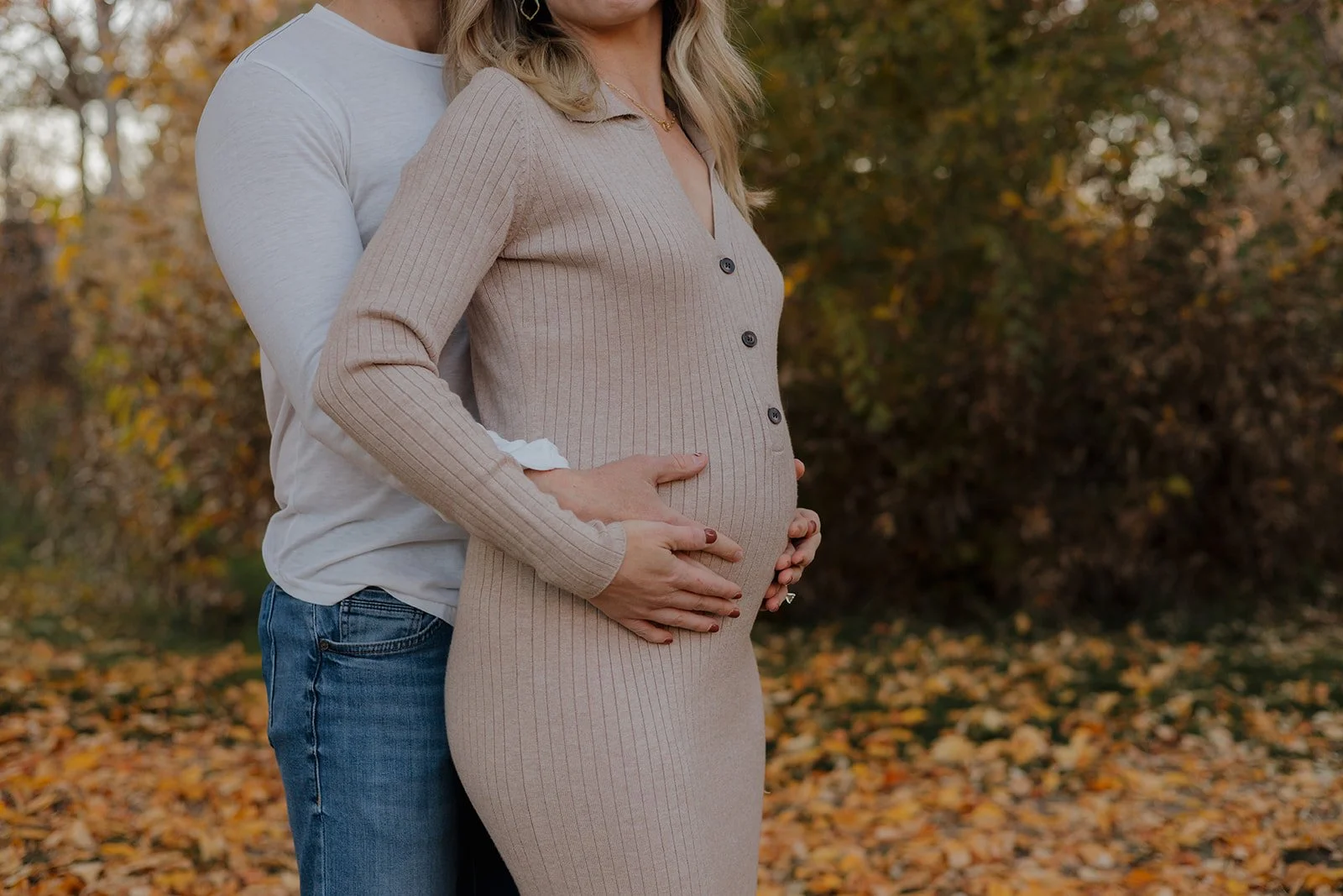 man and woman holding each other with hands over a baby bump